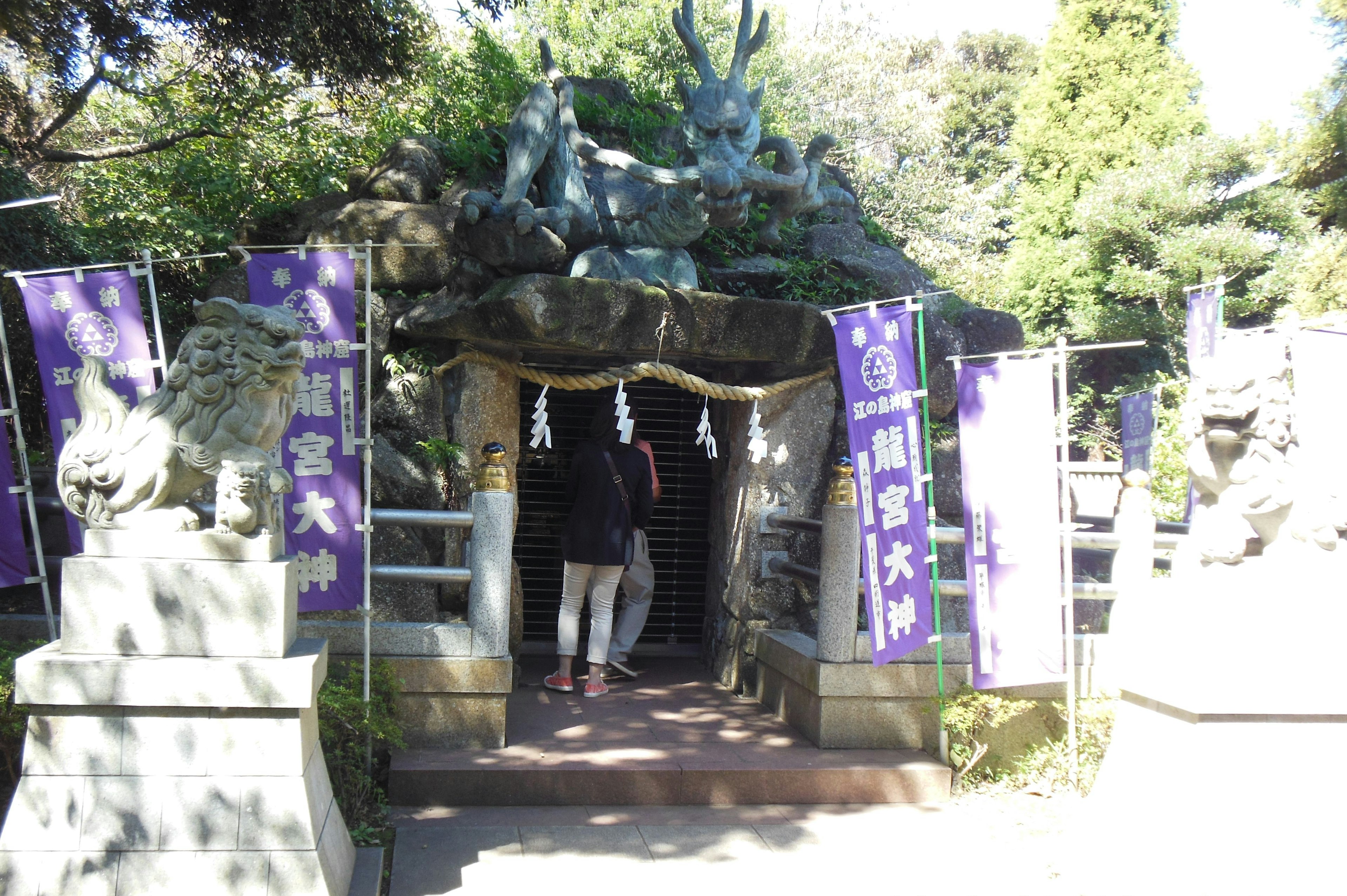 Entrée d'une grotte de sanctuaire avec des bannières violettes et des statues en pierre