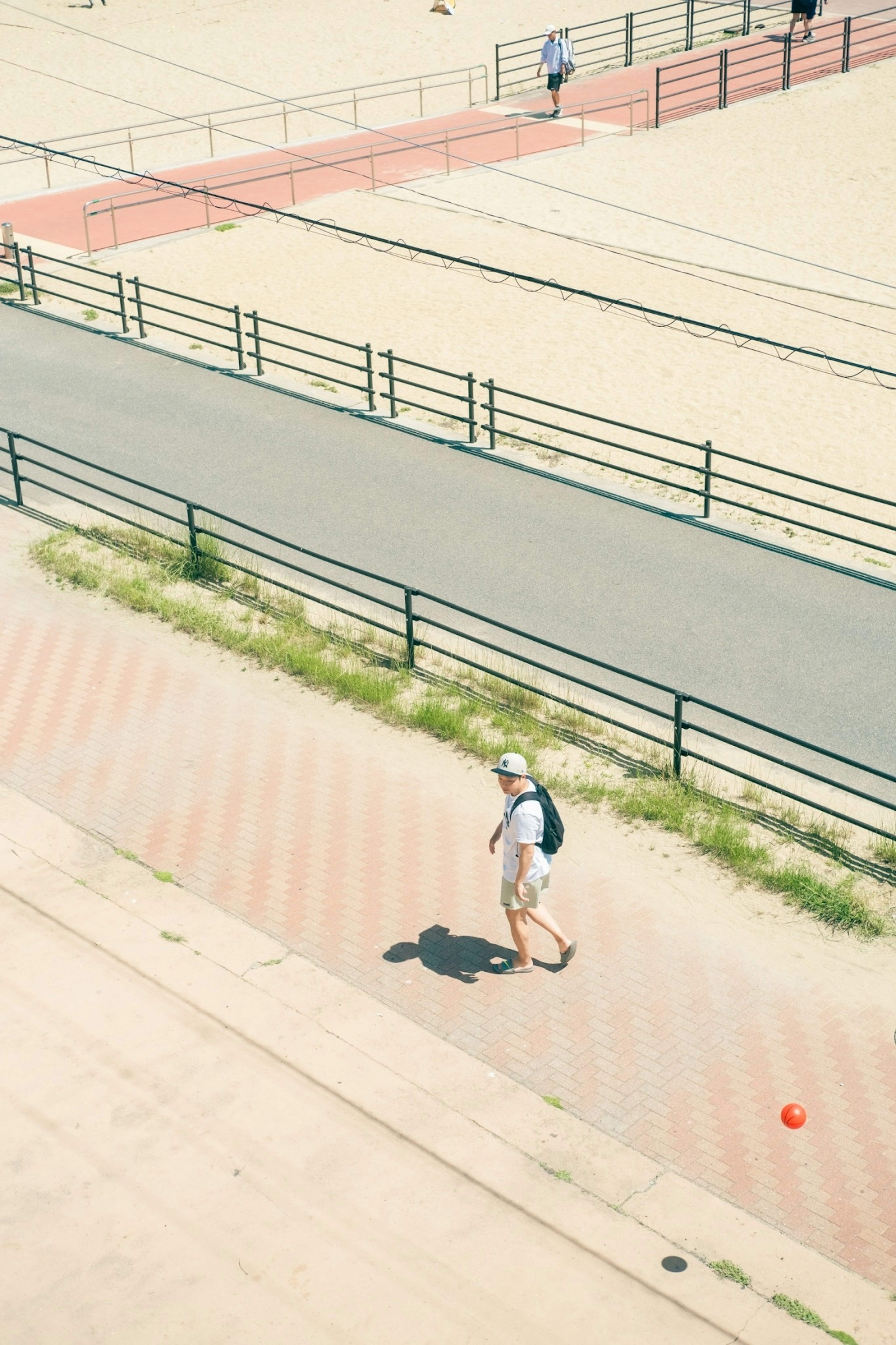 海辺の歩道を歩く人物と砂浜の風景