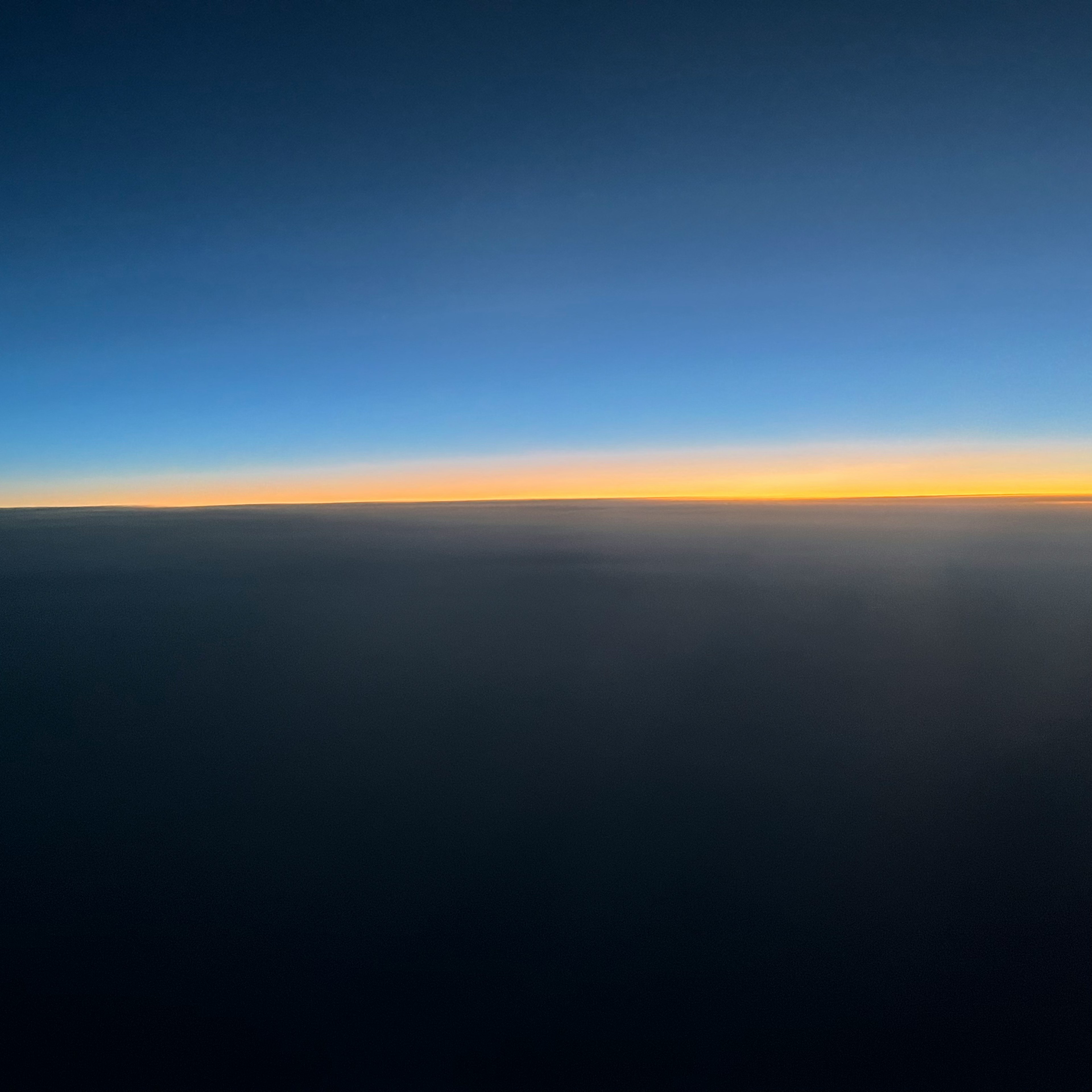 Blauer Himmel mit orangefarbenem Sonnenuntergang am Horizont sichtbar