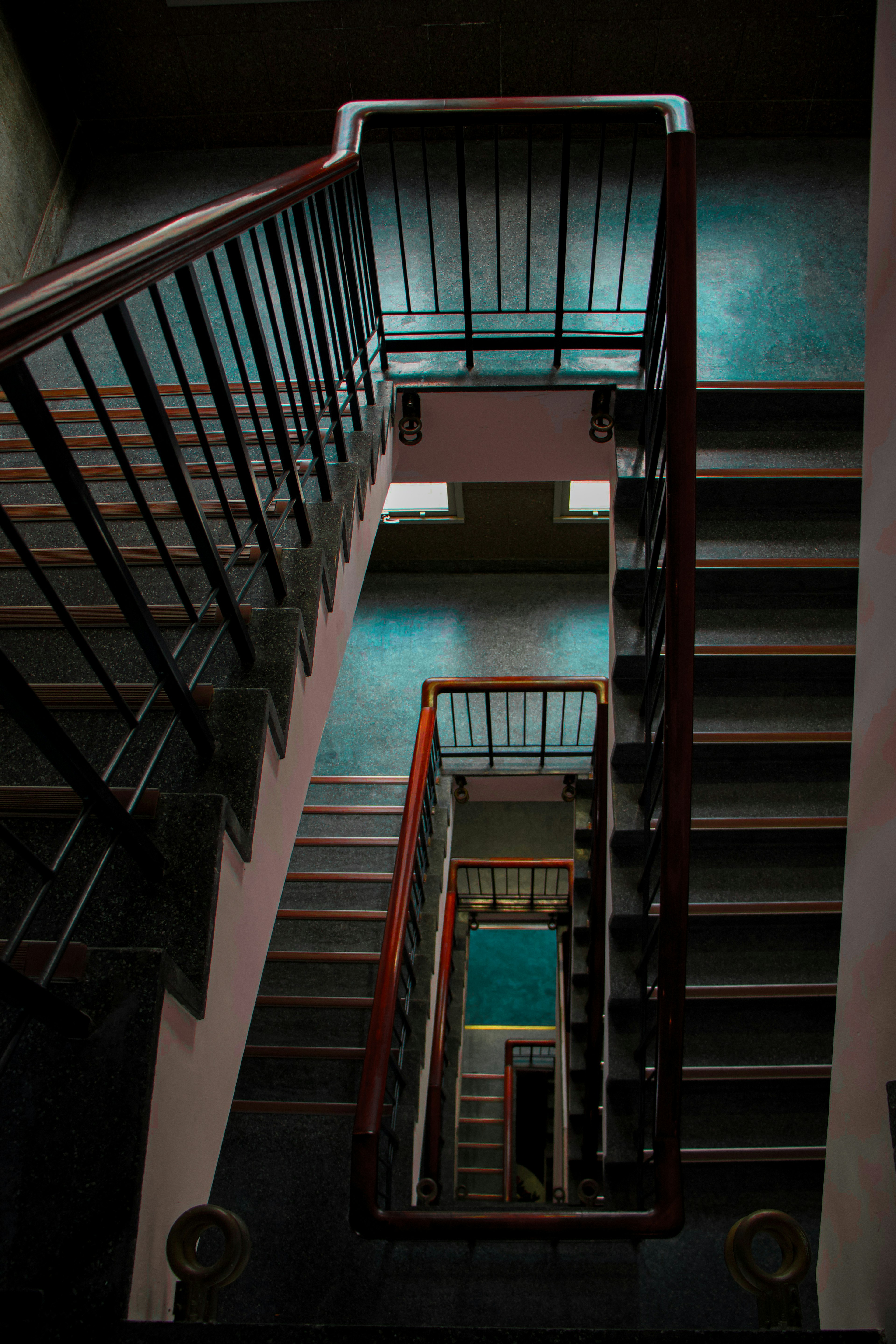 View from the top of a staircase looking down featuring metal railings and dark tones