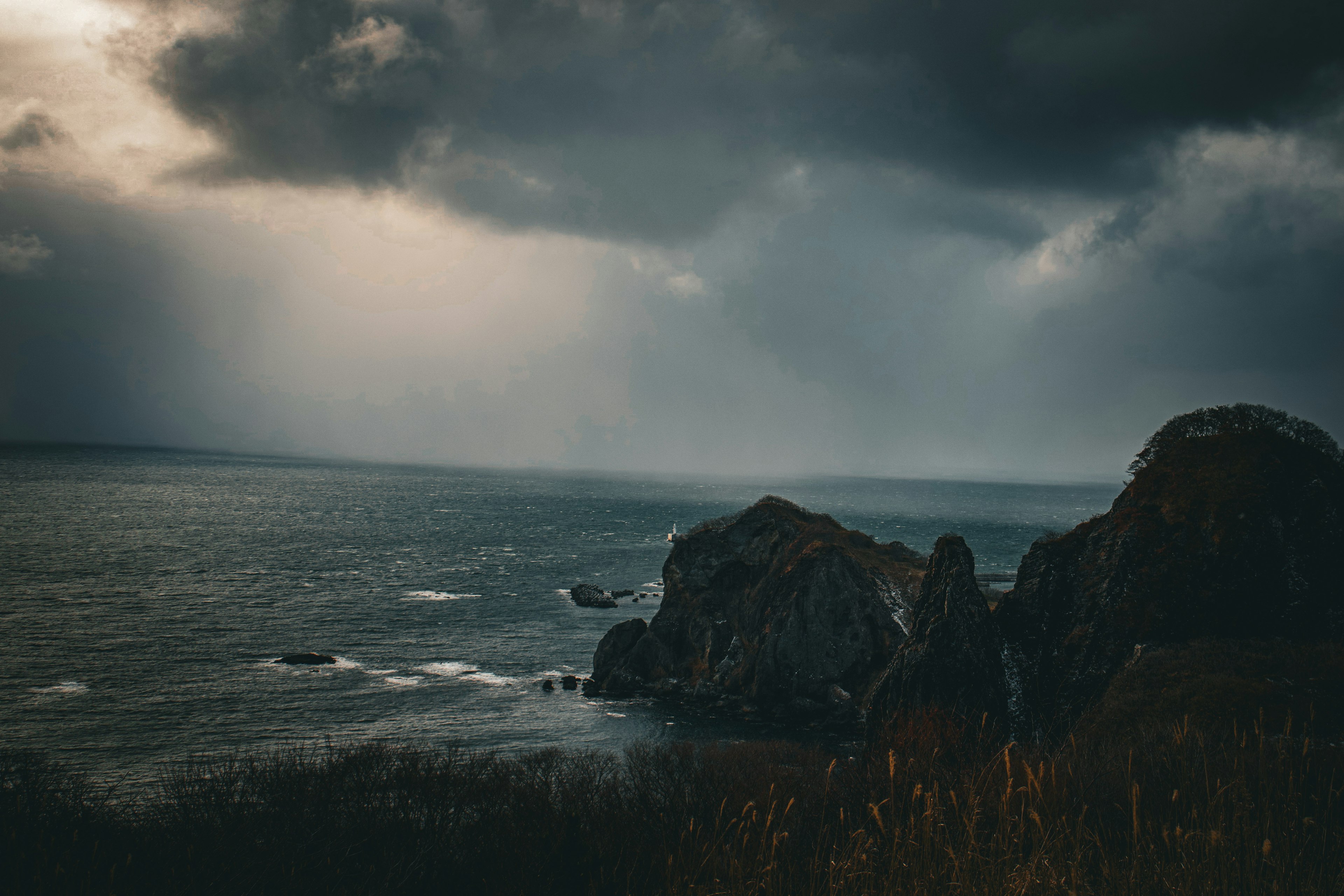 A dramatic seascape with dark clouds and rugged rocks