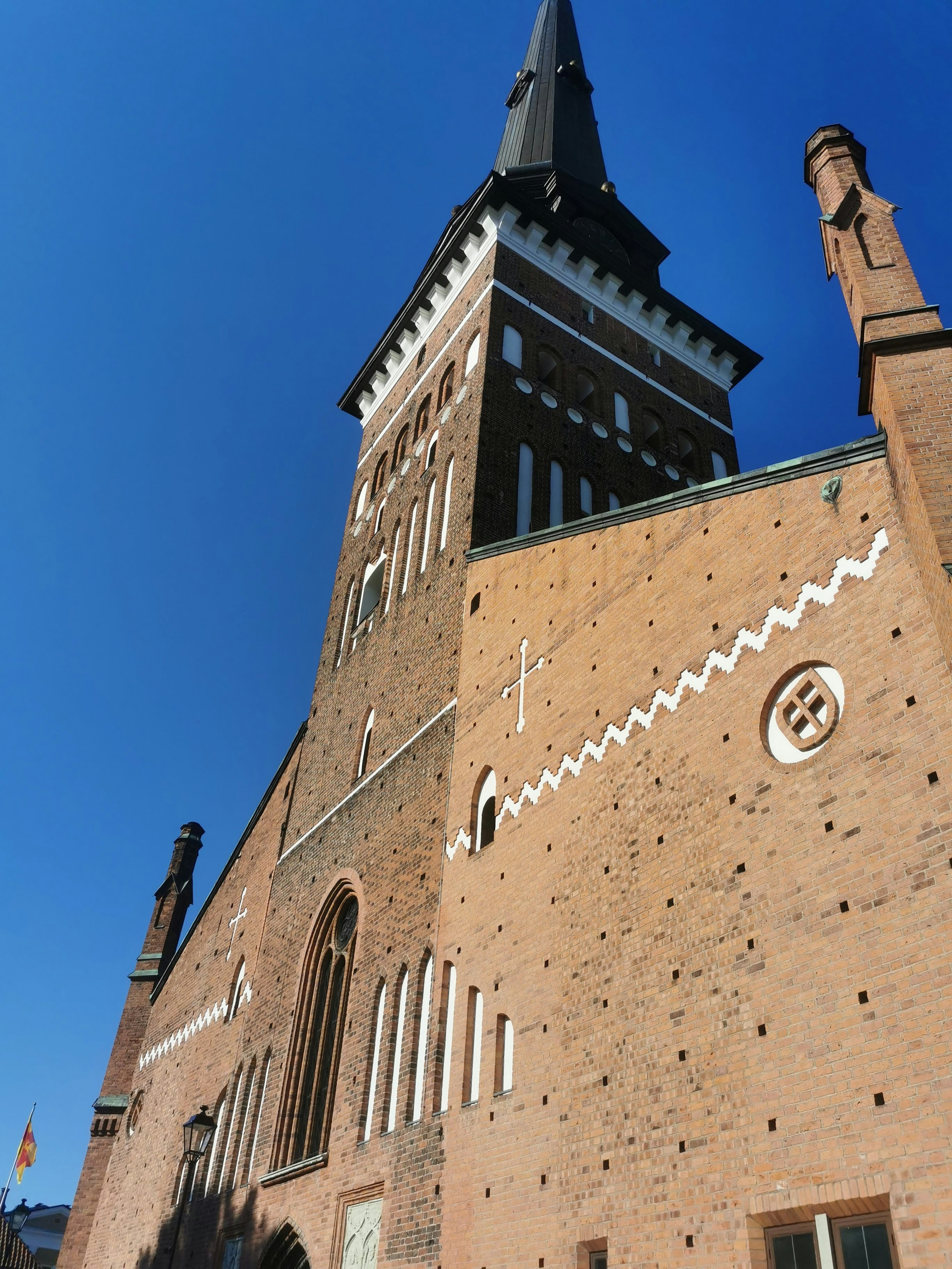 Vue latérale d'une église avec un clocher élancé et des murs en briques distinctifs