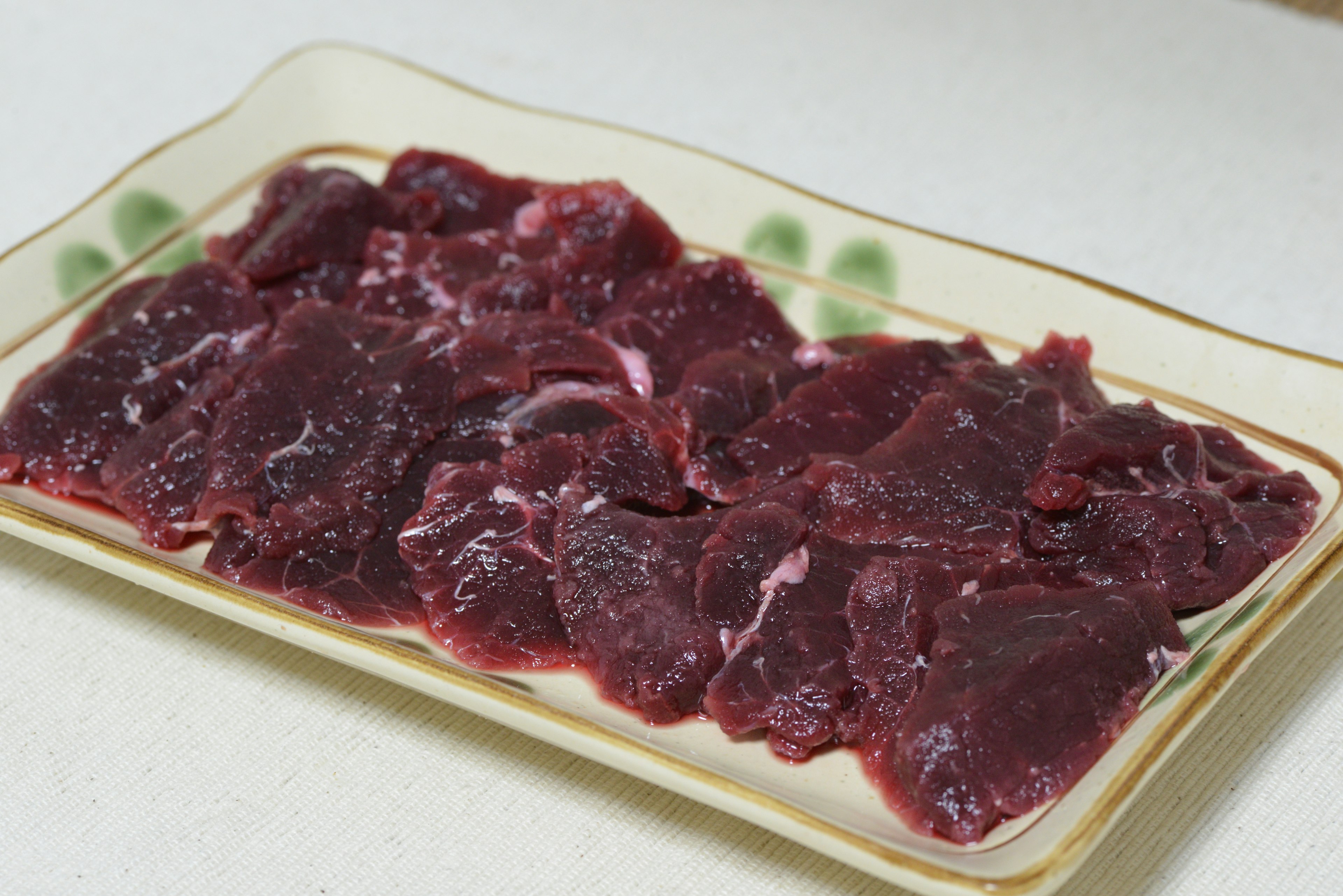 Thinly sliced raw meat arranged on a plate