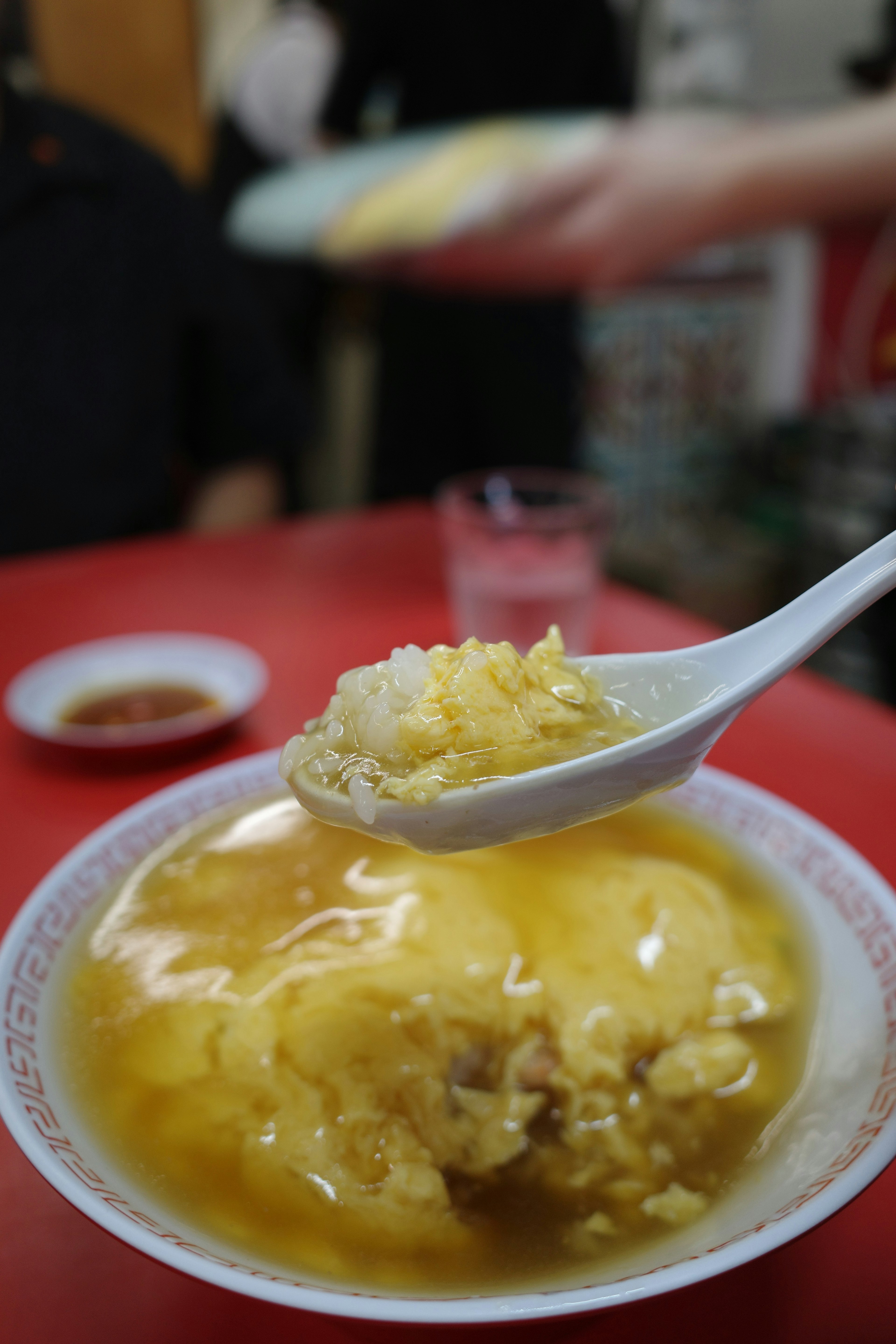 Spoon with egg and rice dish and background person