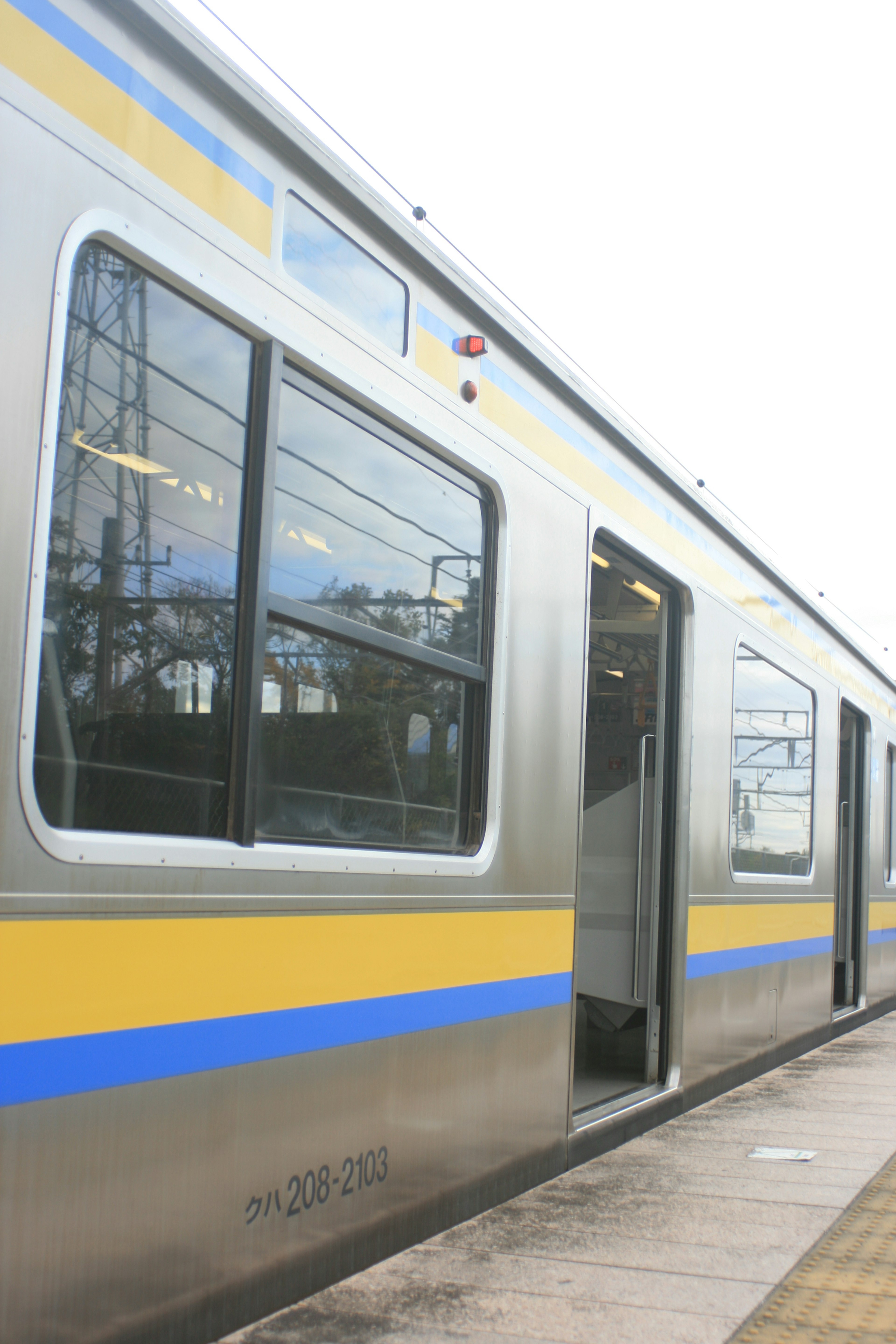 Vue latérale d'un train argenté avec des rayures bleues et jaunes