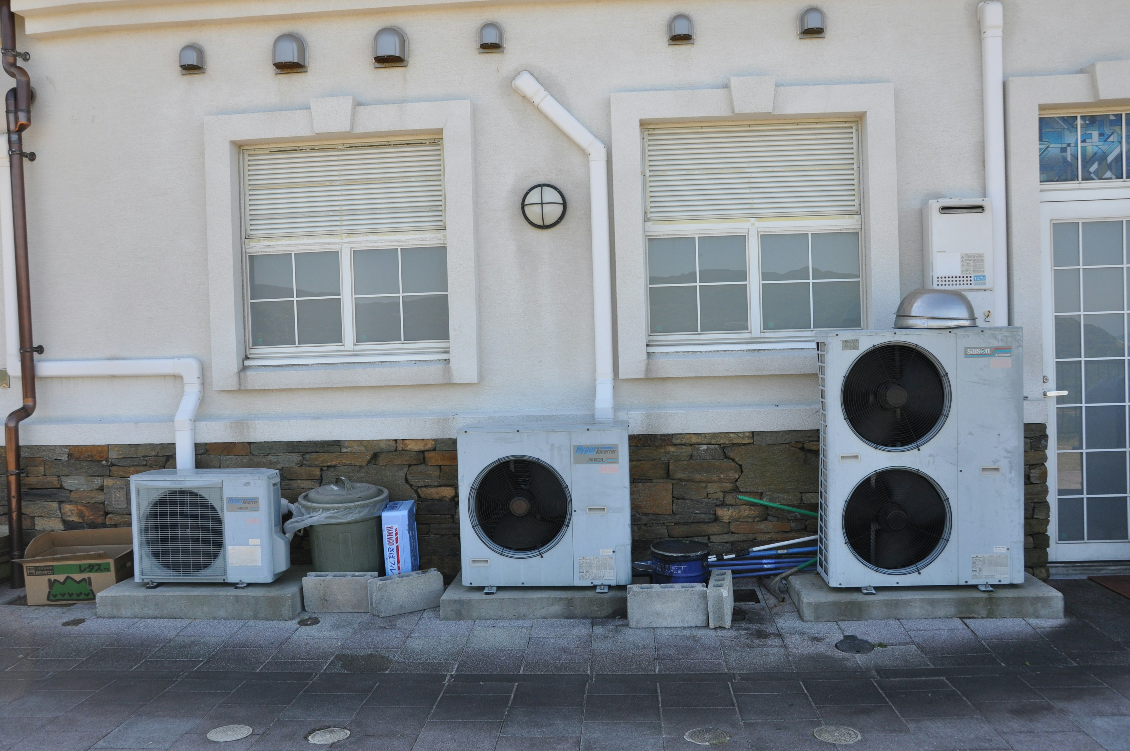 Air conditioning units mounted on a wall with a clock visible