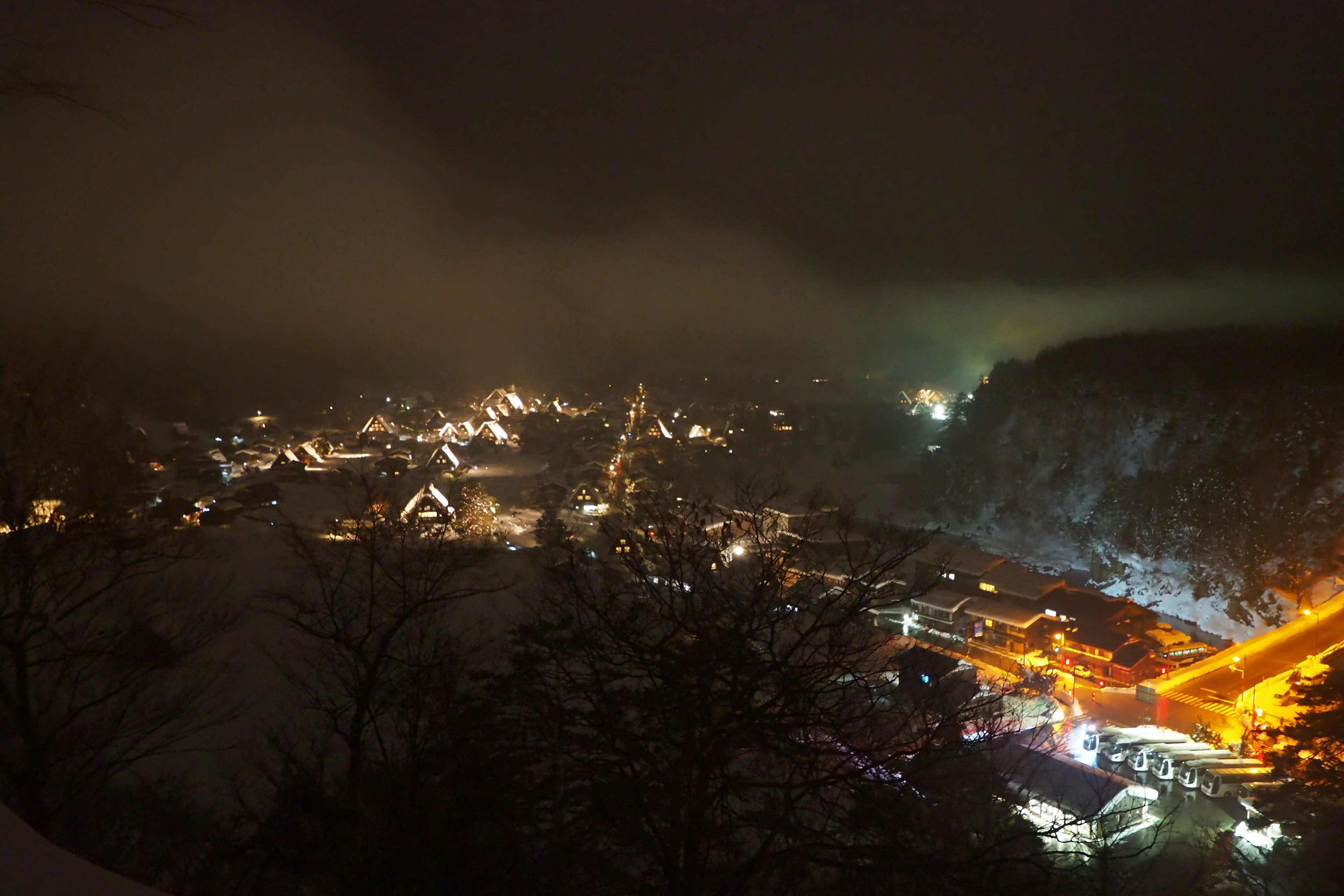 A picturesque night view of a town illuminated by lights with a misty atmosphere