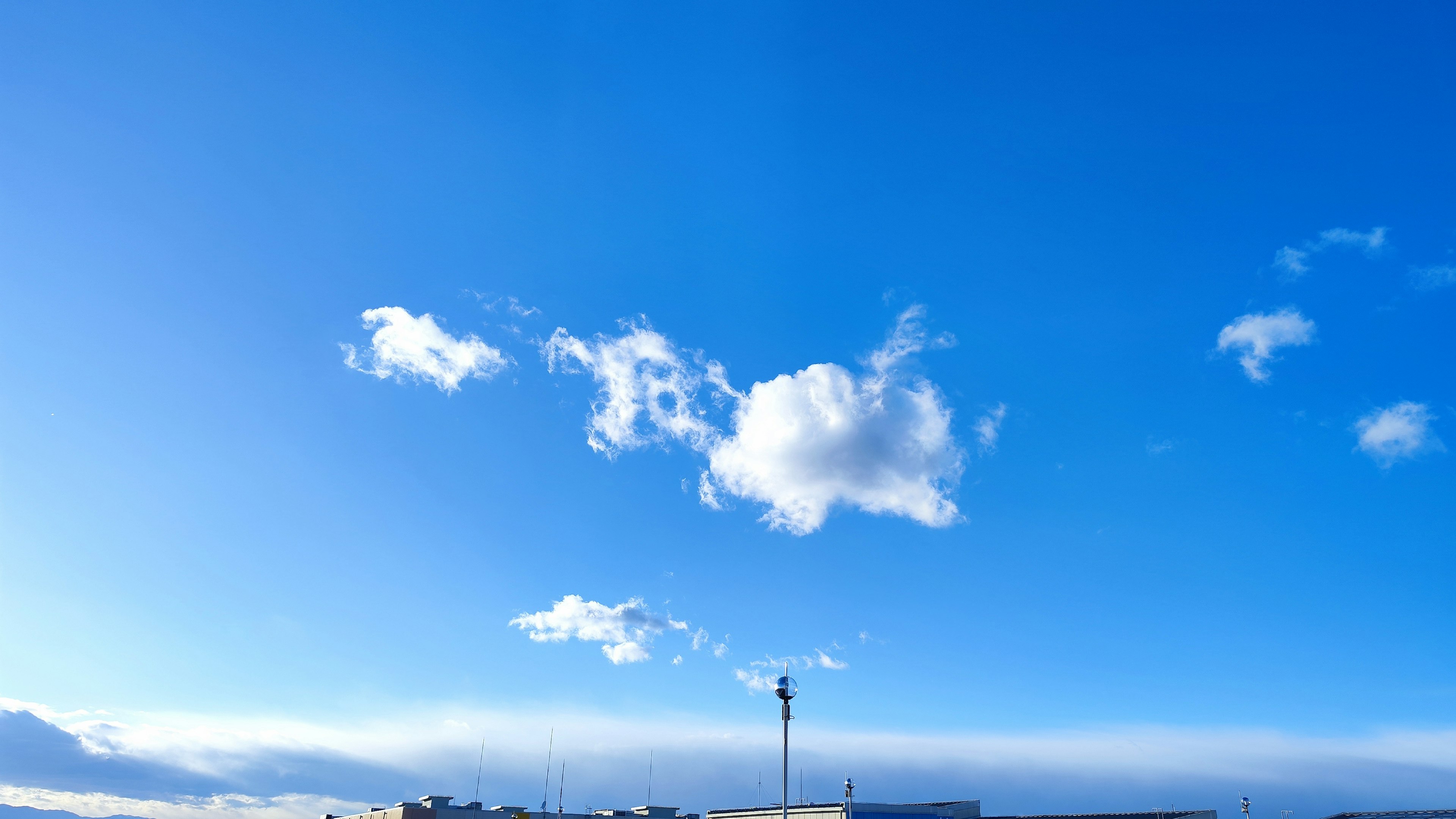 Nubes blancas flotando en un cielo azul con siluetas de edificios