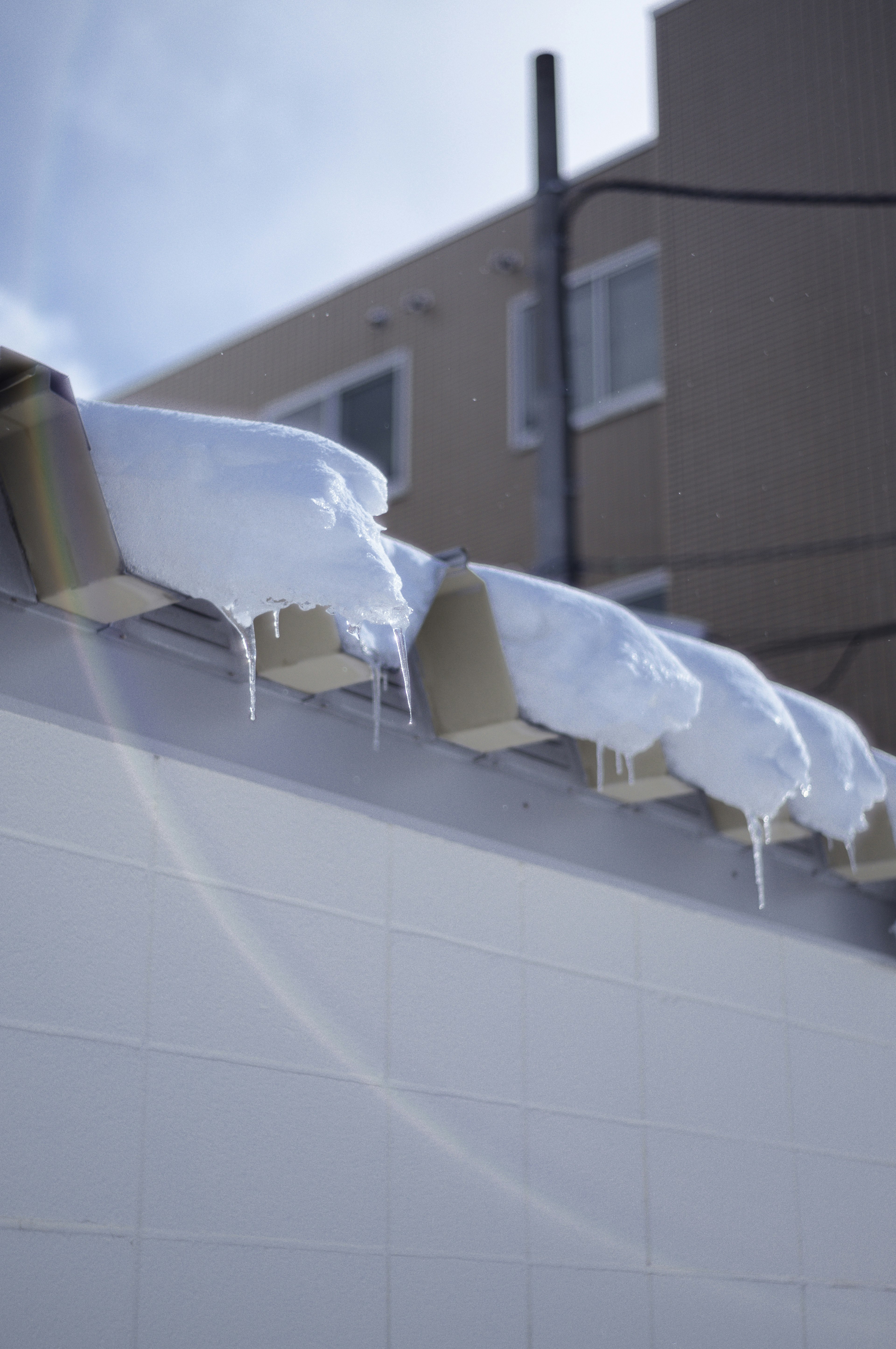 雪が積もった屋根と氷柱が見える冬の風景