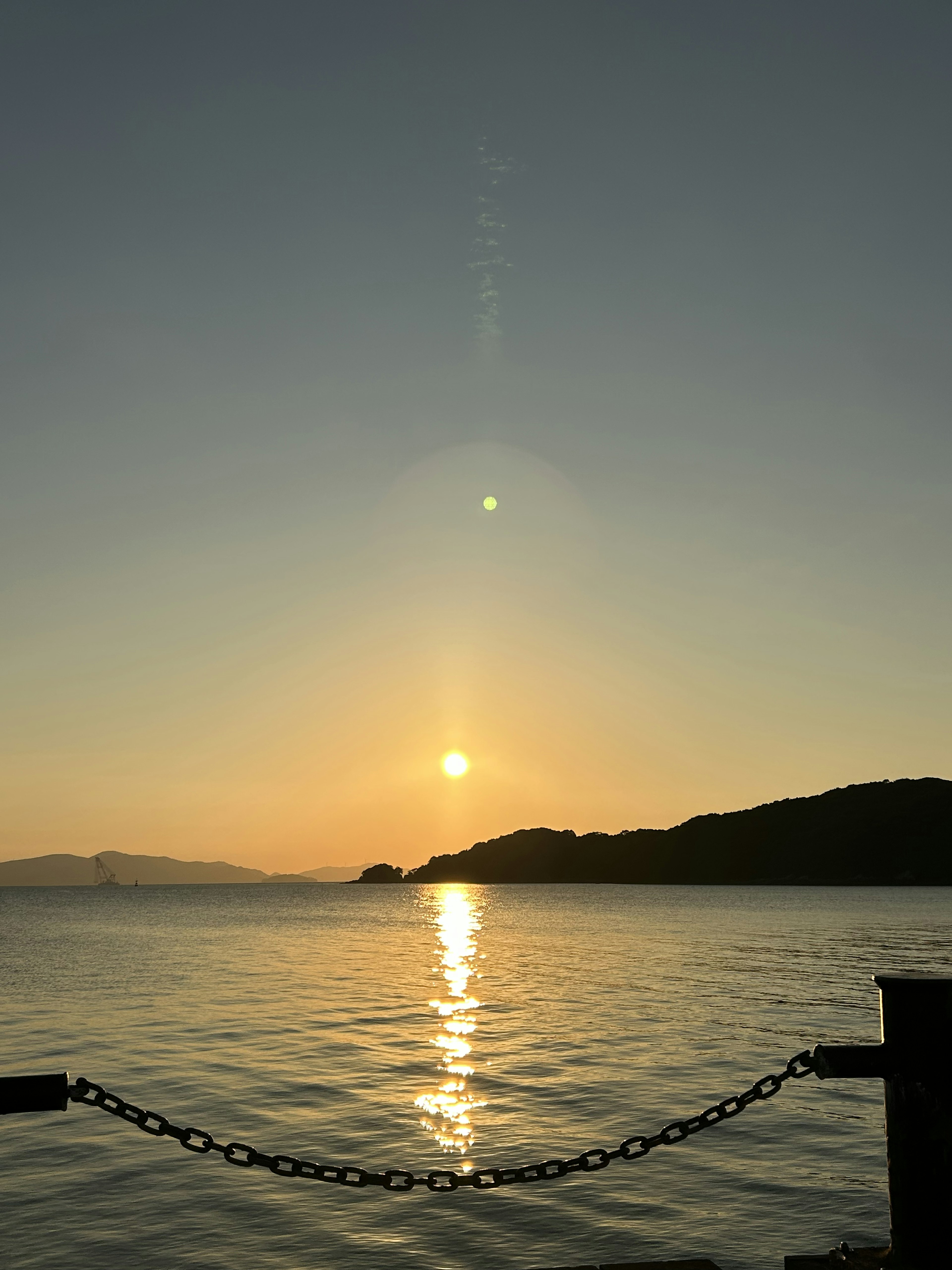 美しい夕日が水面に反射している風景、山のシルエット、穏やかな海