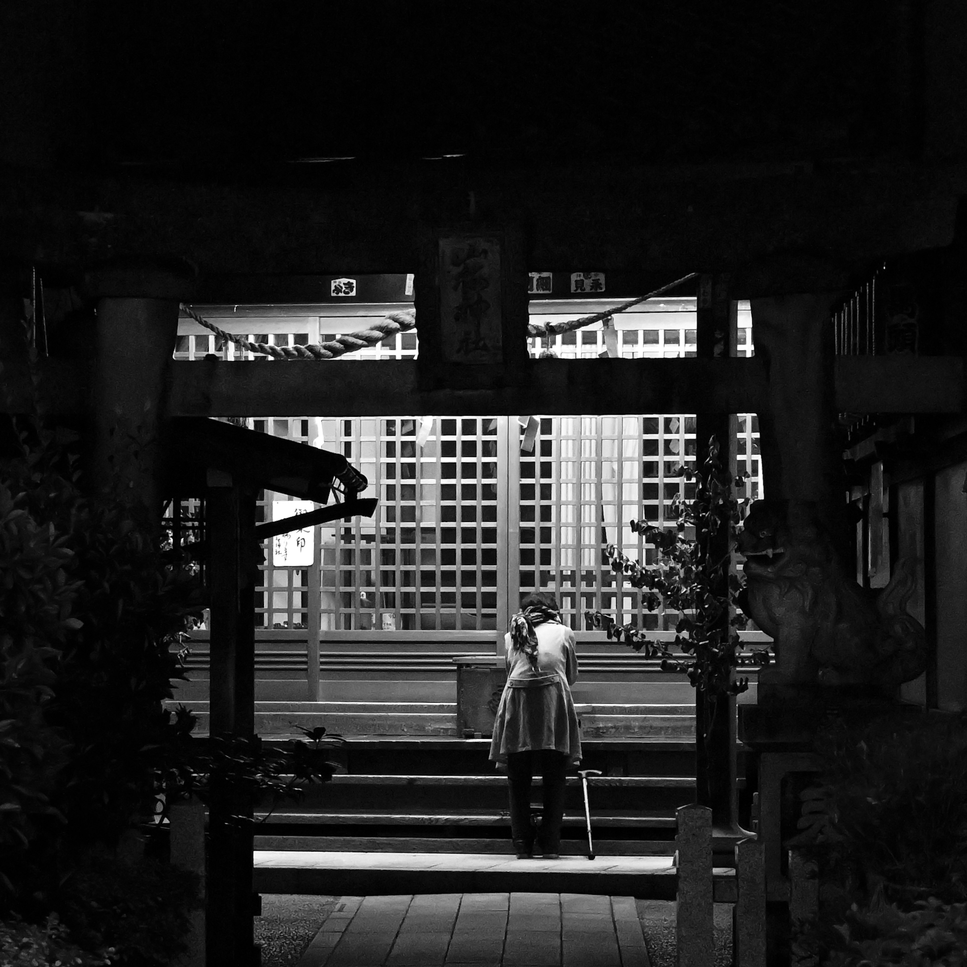 夜の神社の門の前に立つ女性のシルエット