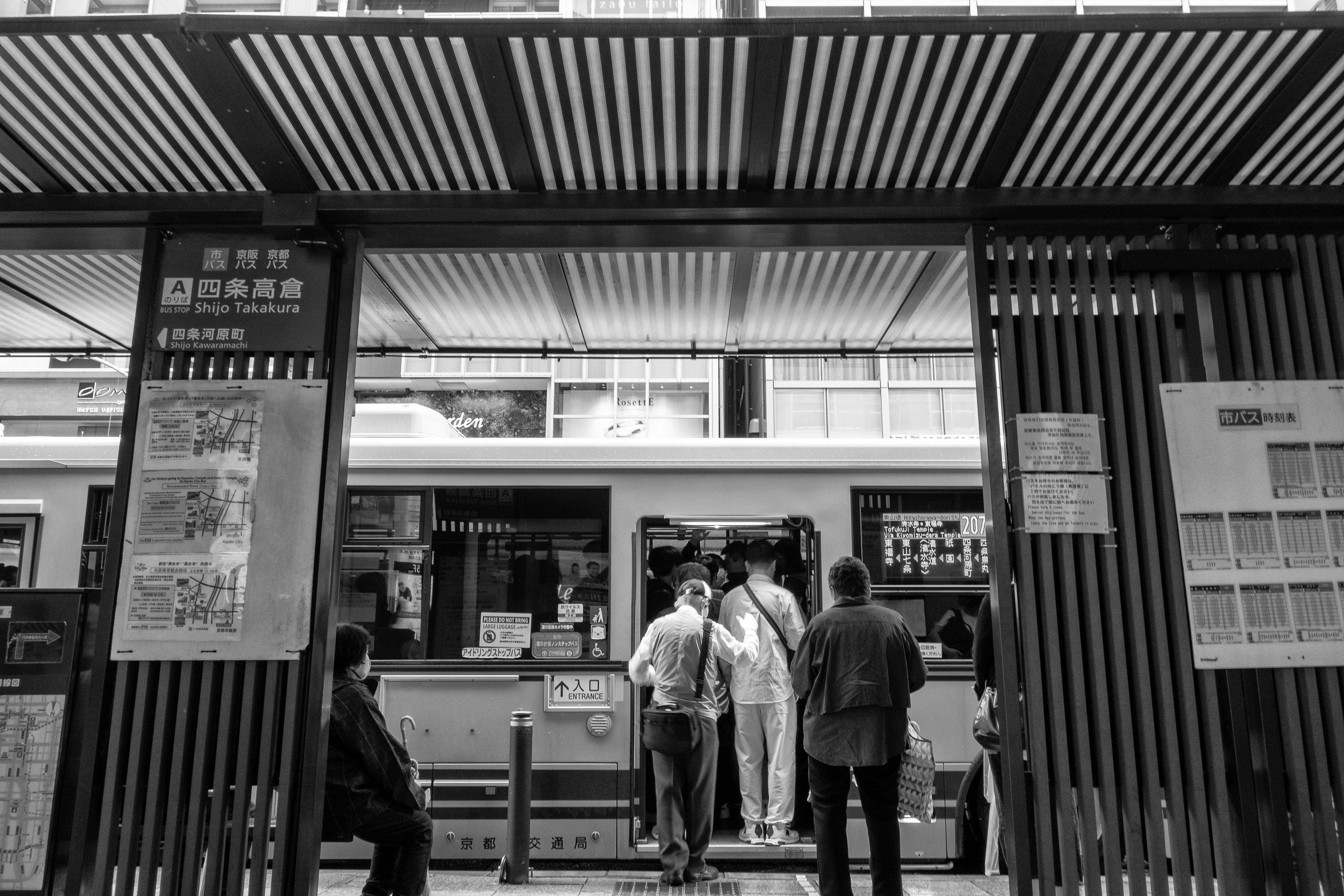 Foto in bianco e nero di persone in attesa al bancone di una stazione