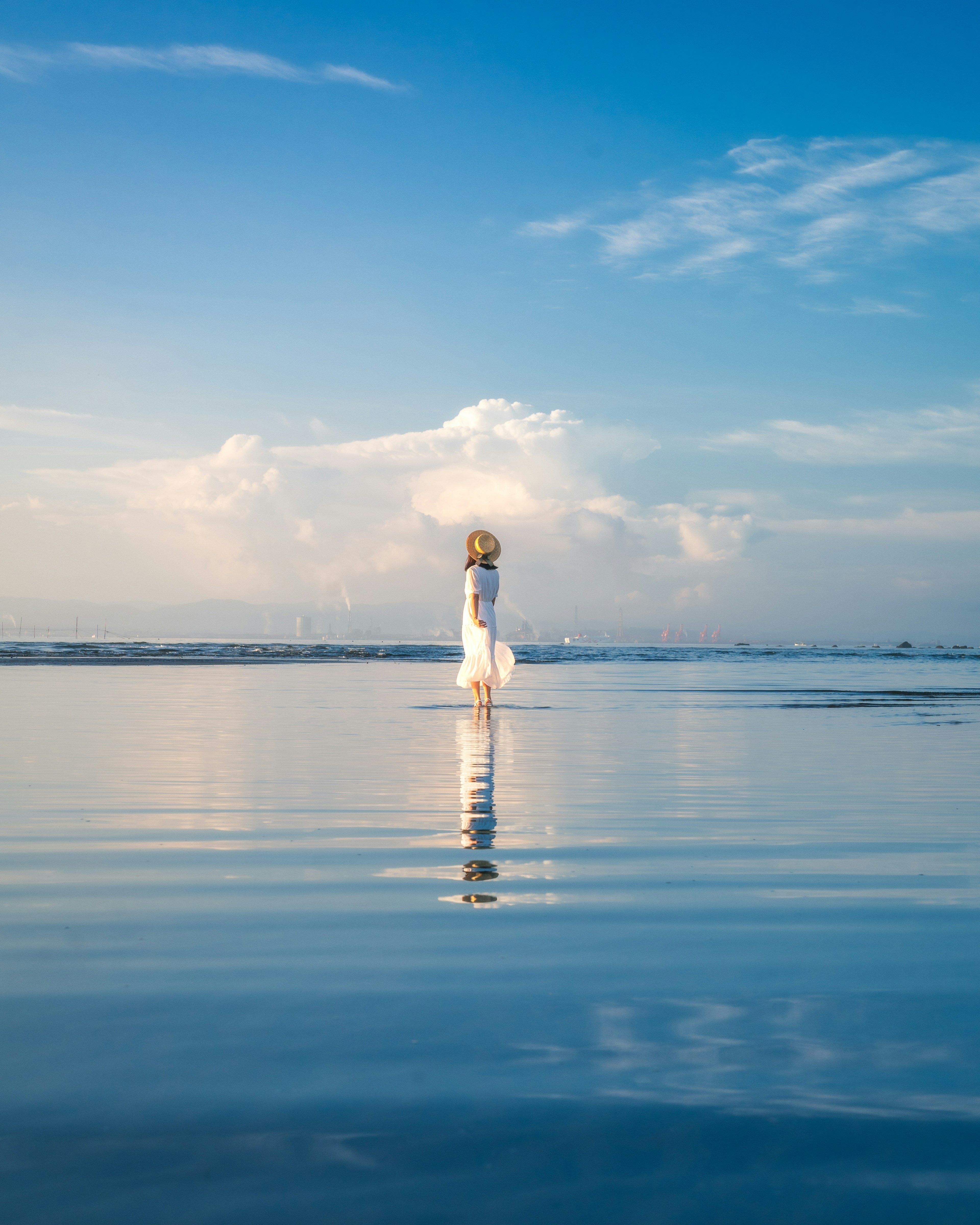 Scenic view of a lighthouse reflecting on calm waters under a blue sky