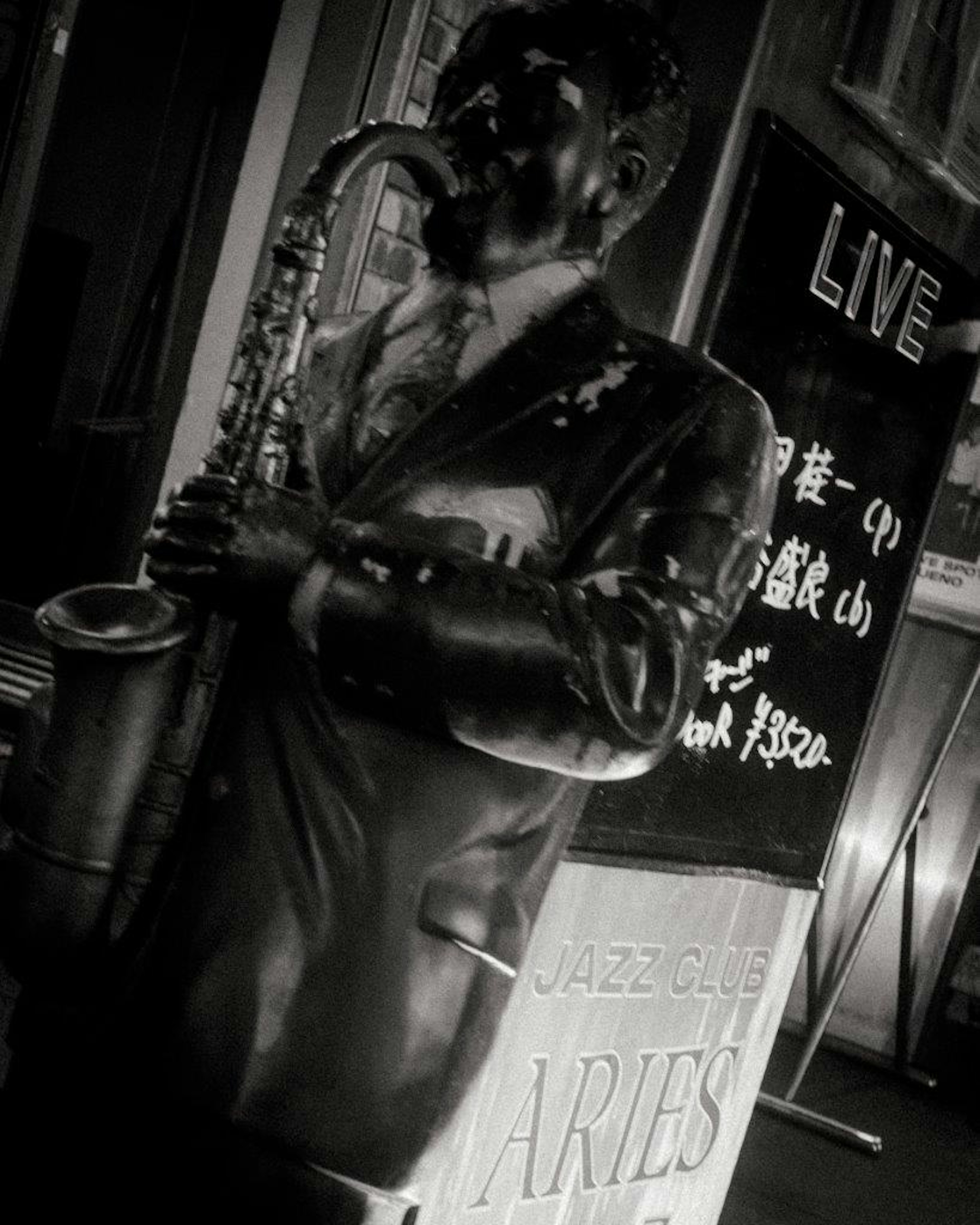 Black statue playing saxophone with live sign