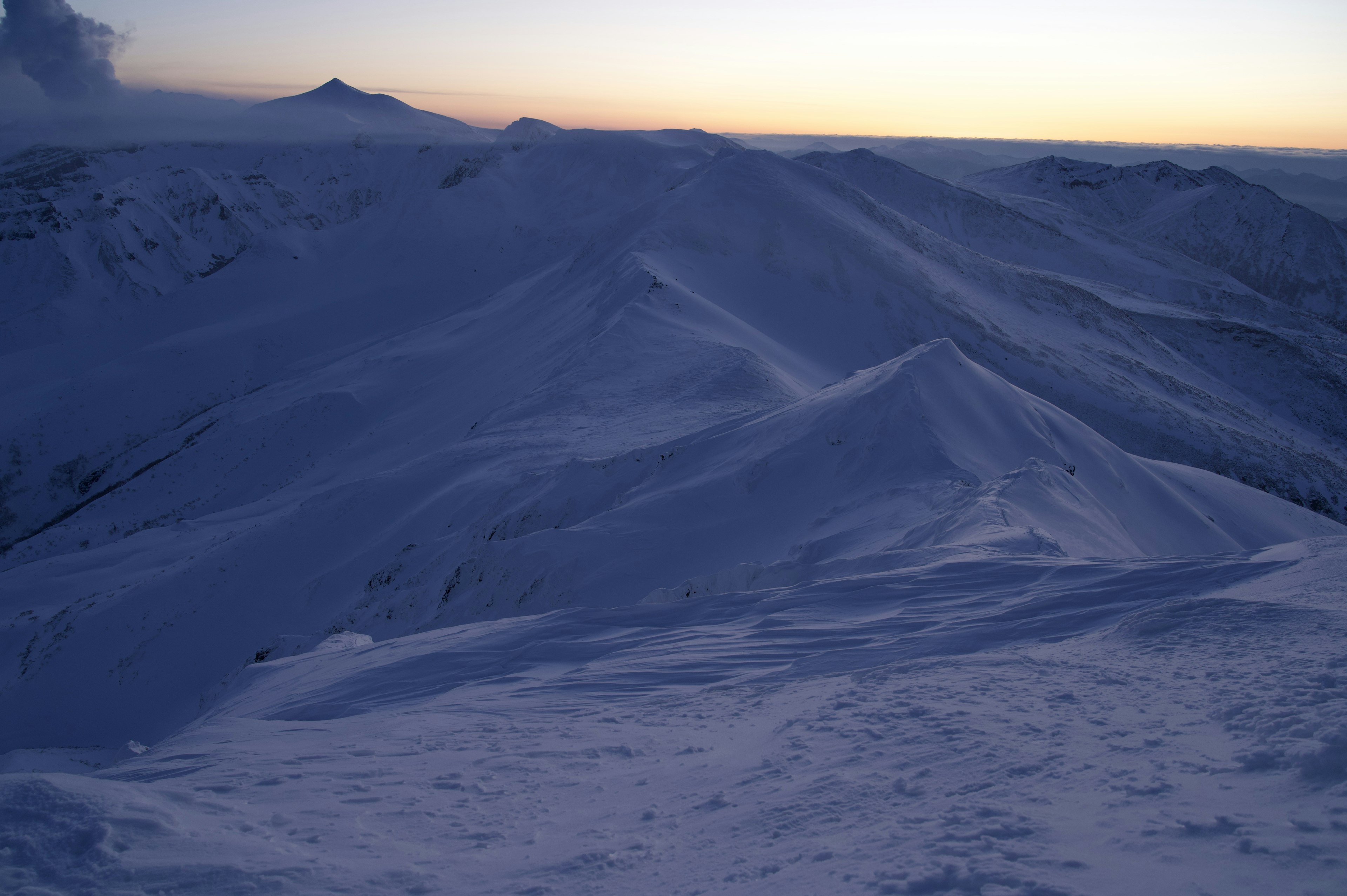 雪に覆われた山脈の壮大な風景と薄明かりの空