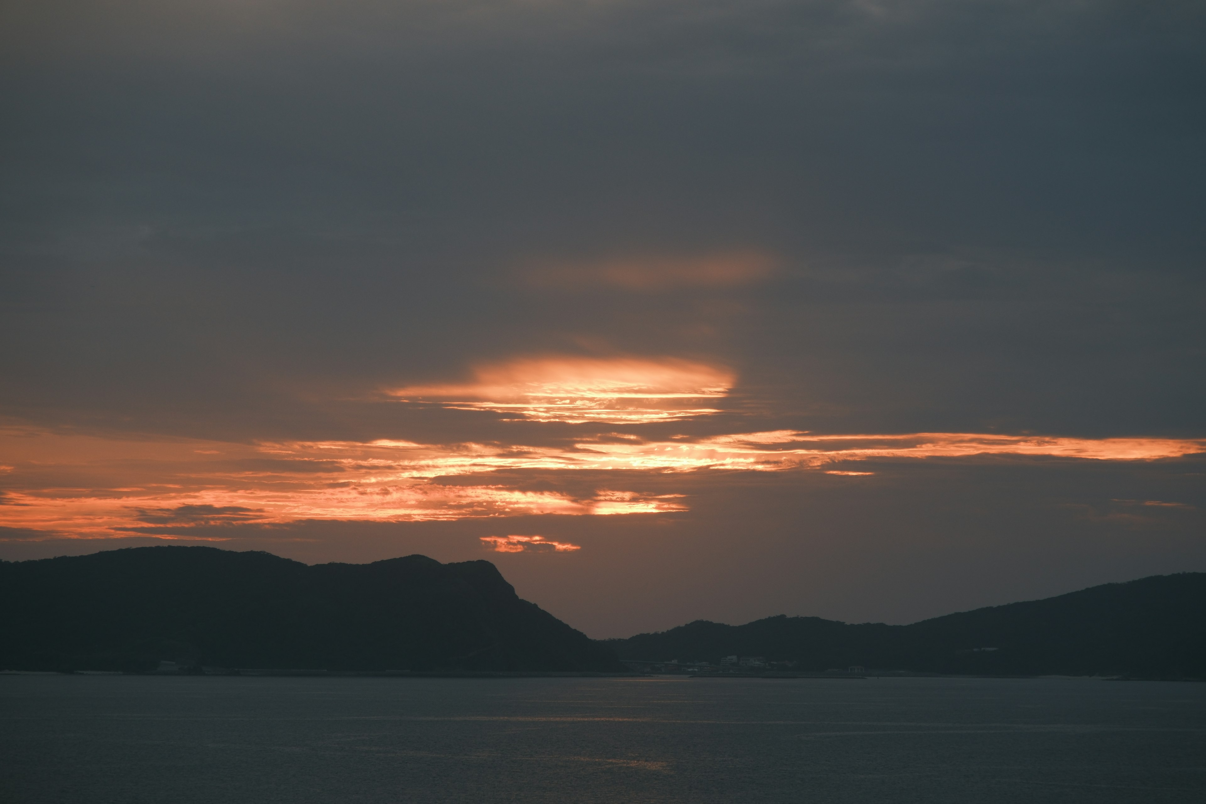 夕焼けの美しい風景が広がる海と山のシルエット