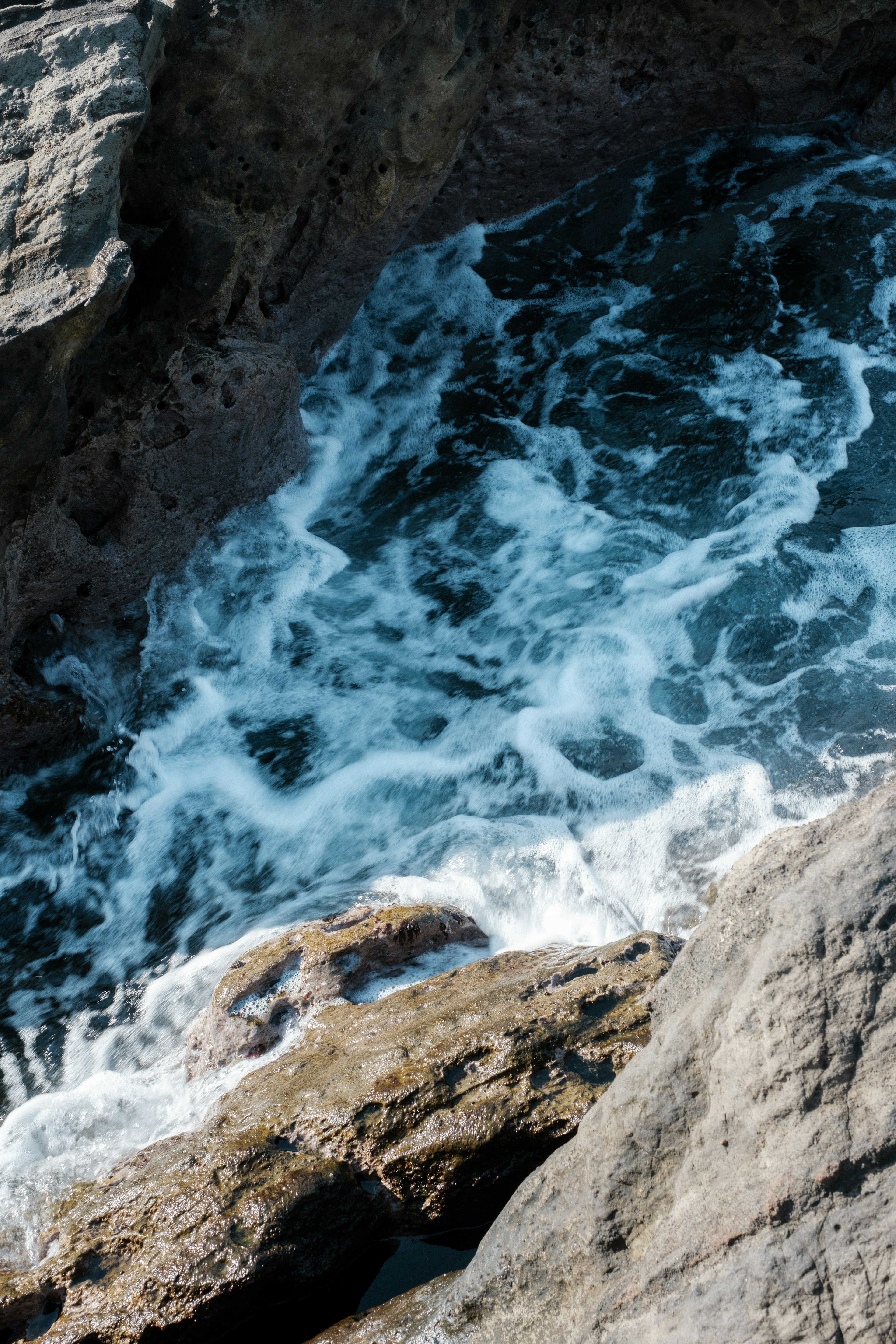 Agua del océano girando alrededor de la costa rocosa