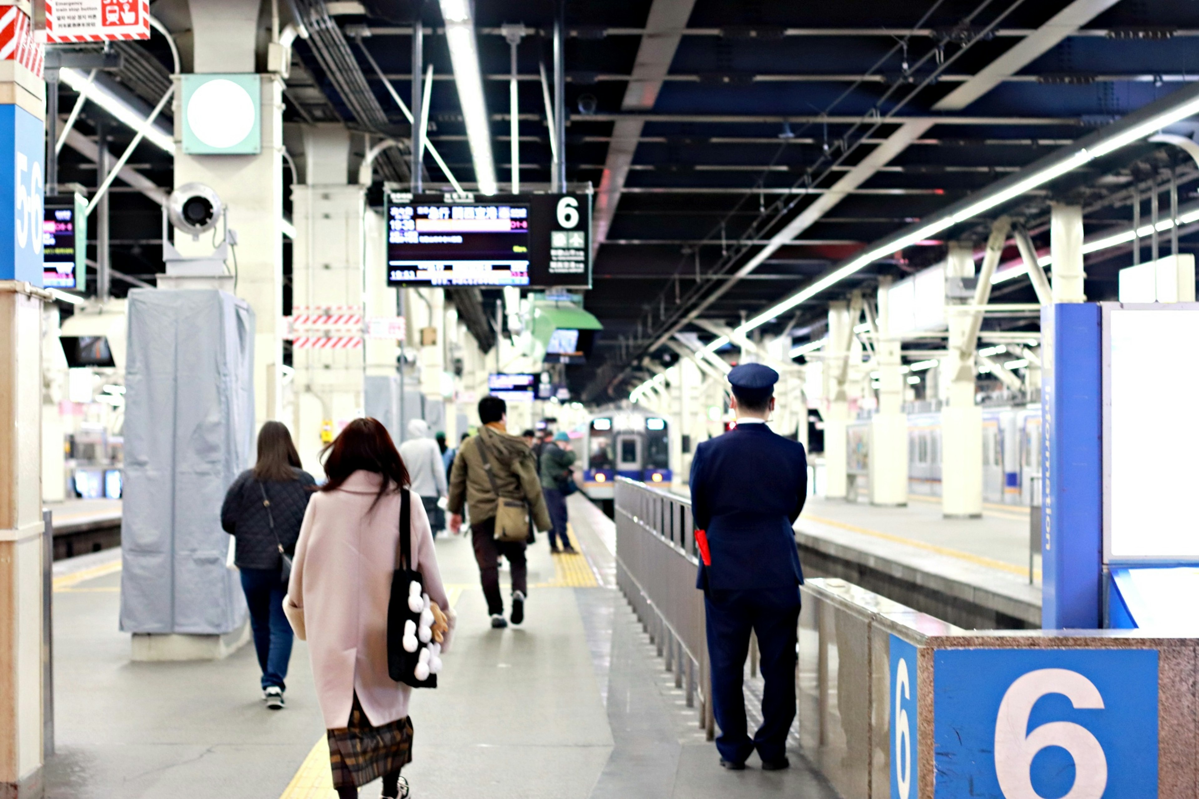 Persone che camminano su un binario con un membro del personale della stazione