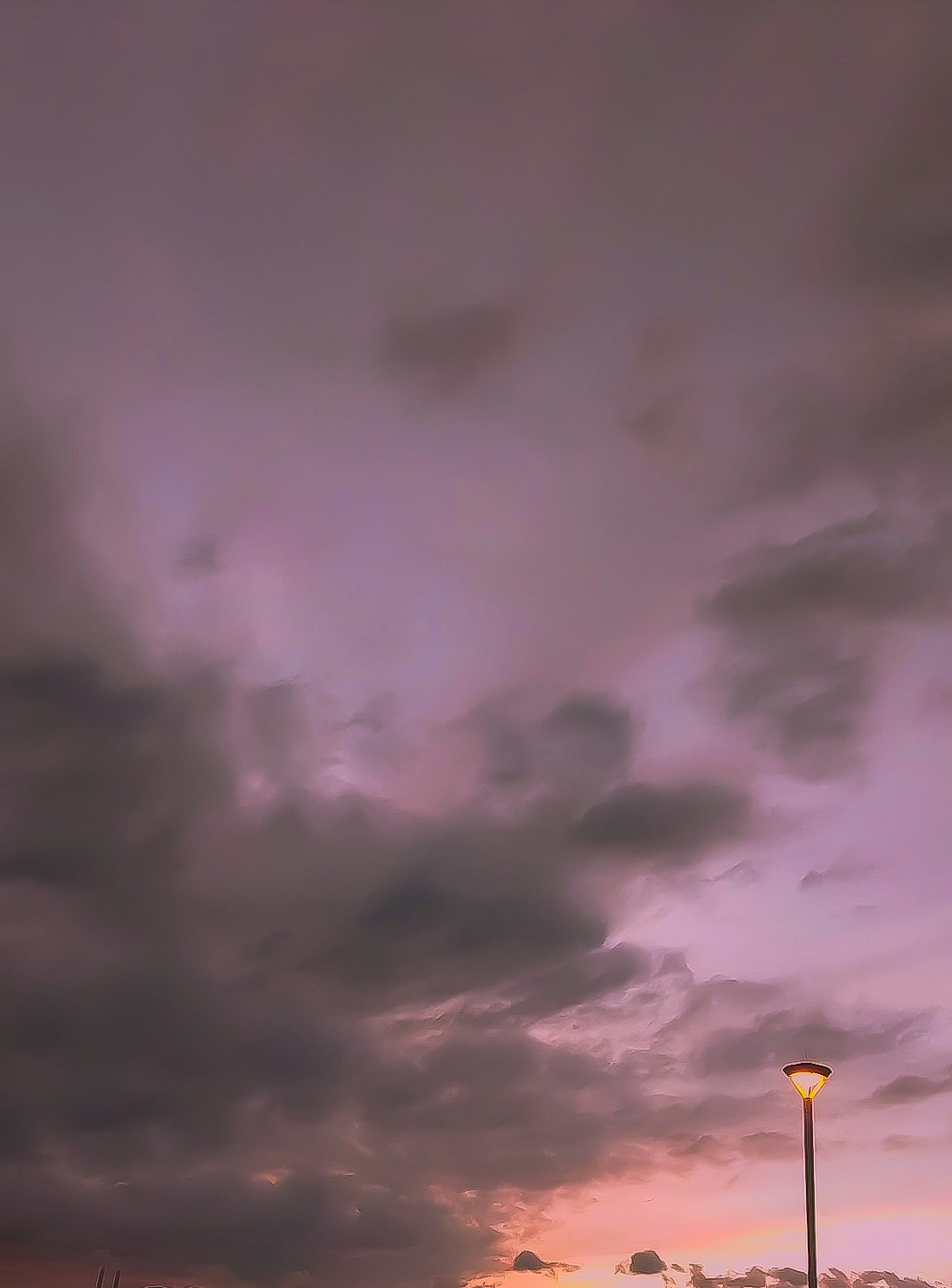 Lila Himmel mit dunklen Wolken und einer Straßenlaterne