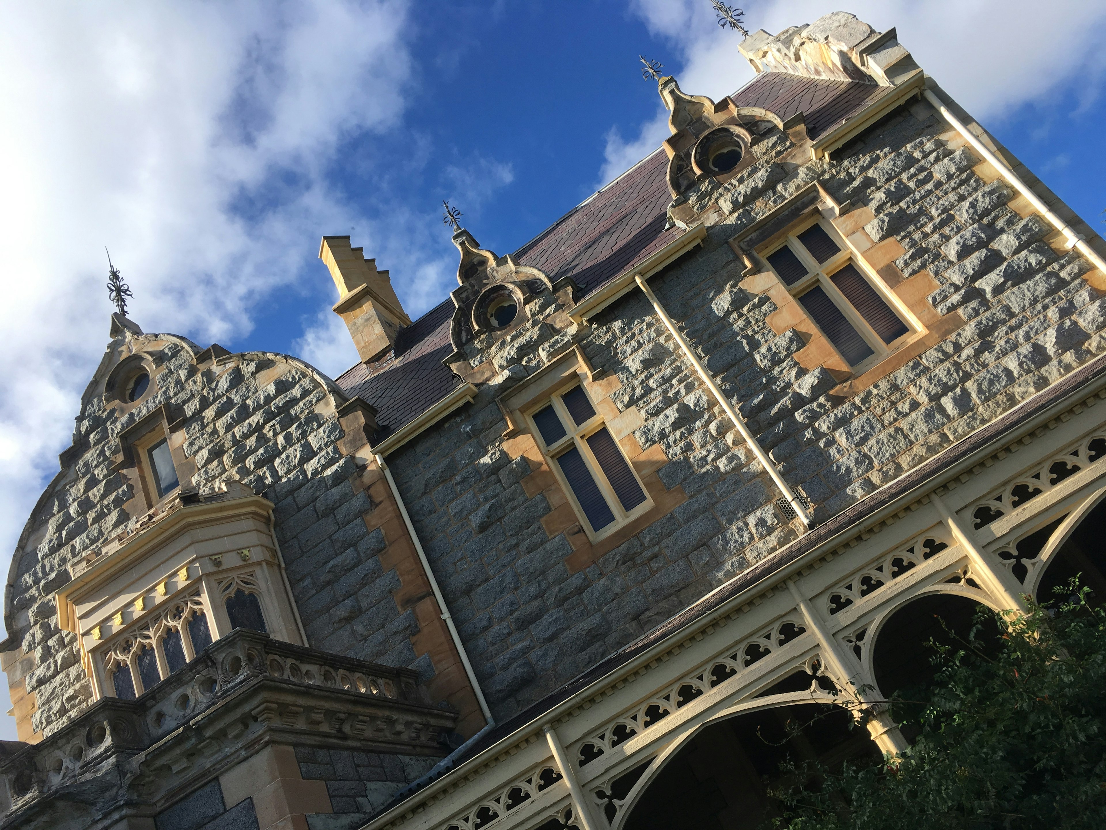 A beautiful stone house with decorative roof and windows against a blue sky