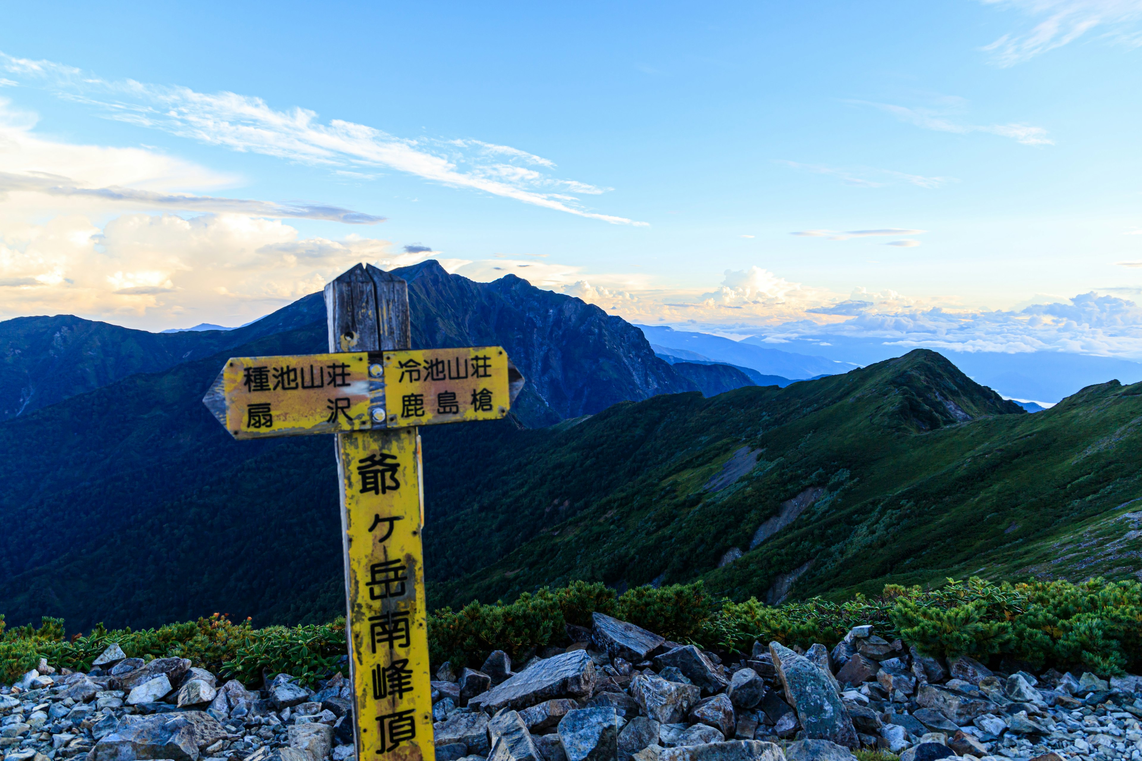 山の頂上に立つ黄色い標識と背景の美しい山々