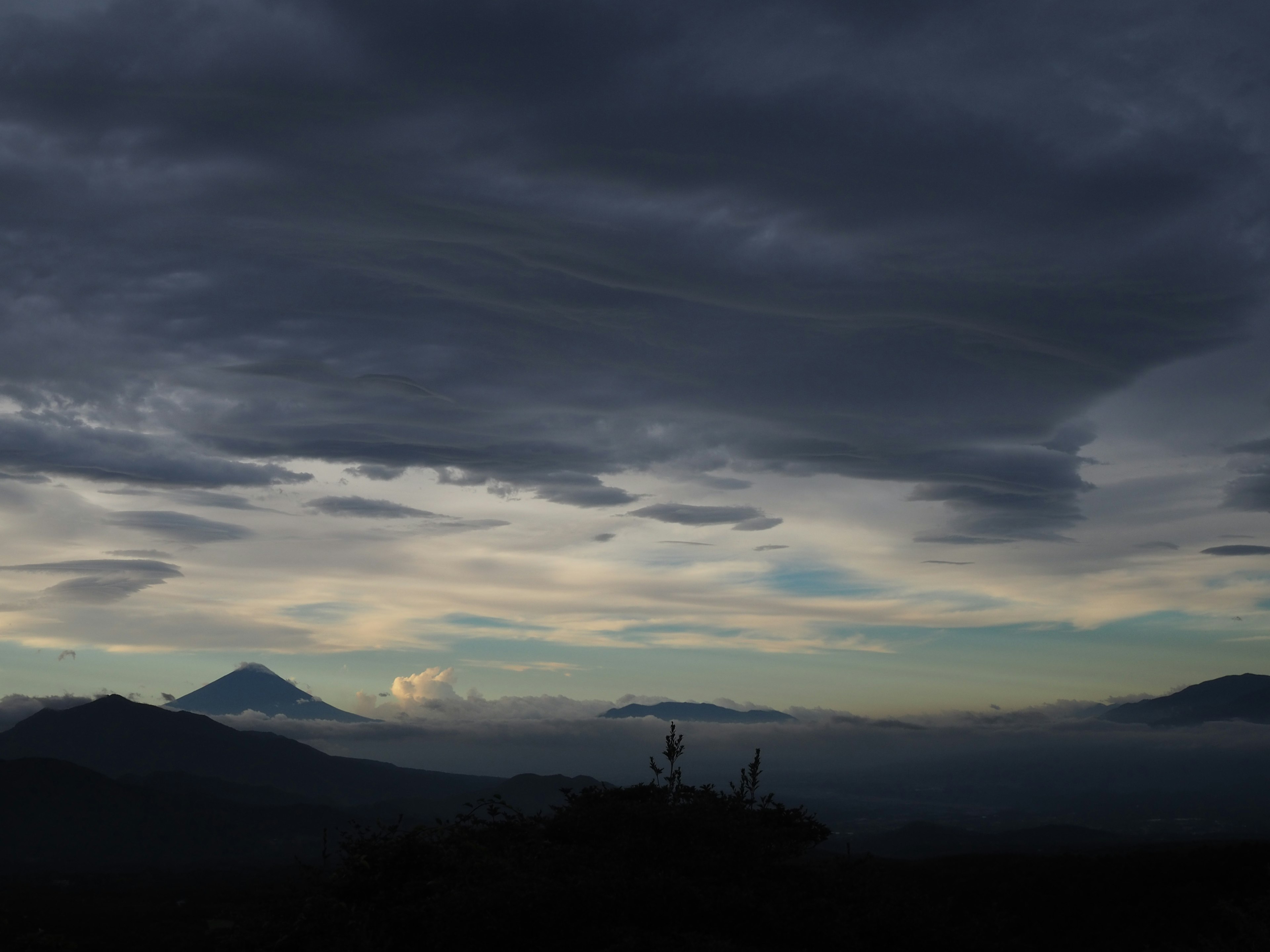 Cielo dramático con nubes oscuras sobre montañas distantes y niebla