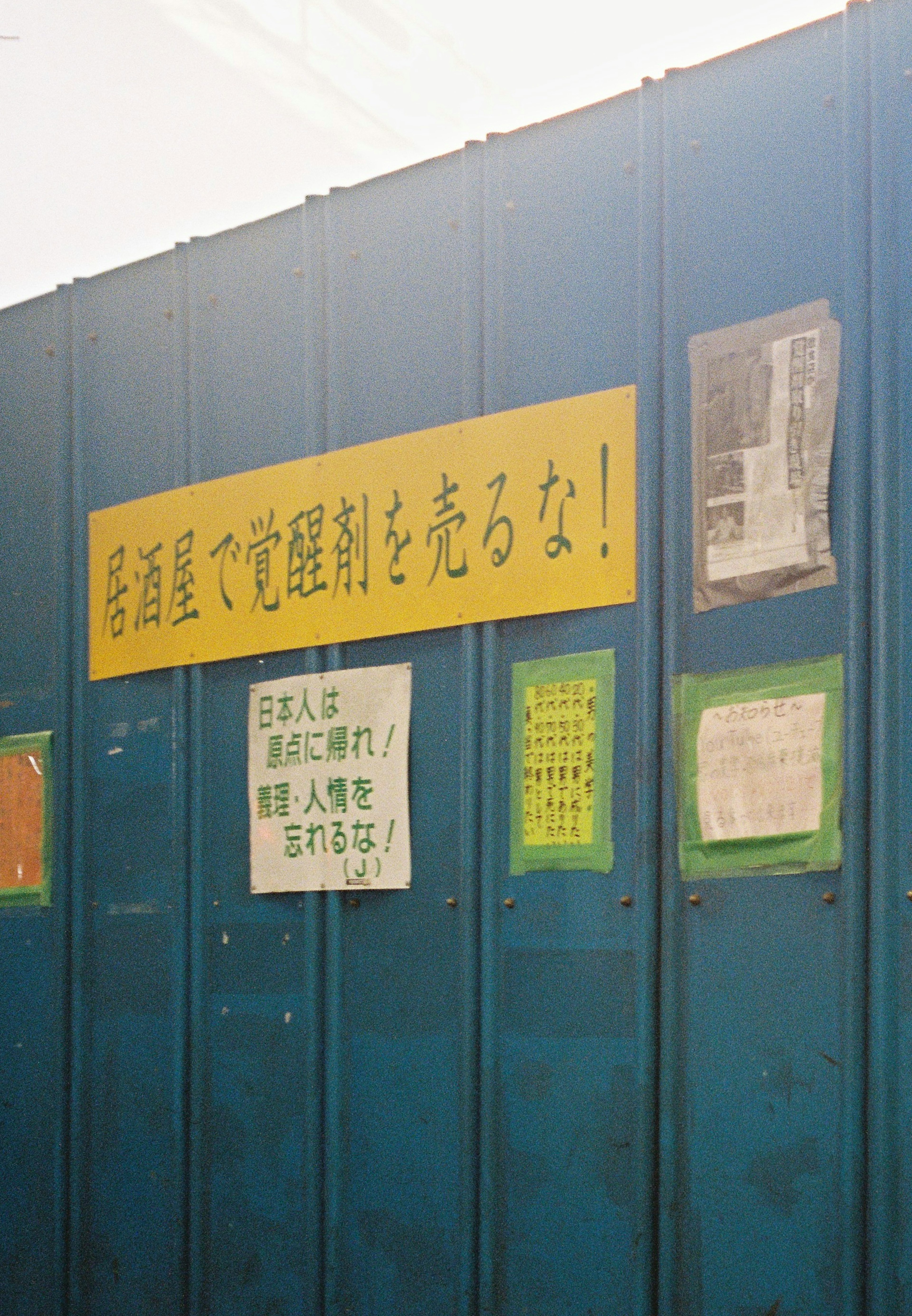 Blue wall with a yellow sign and several posters