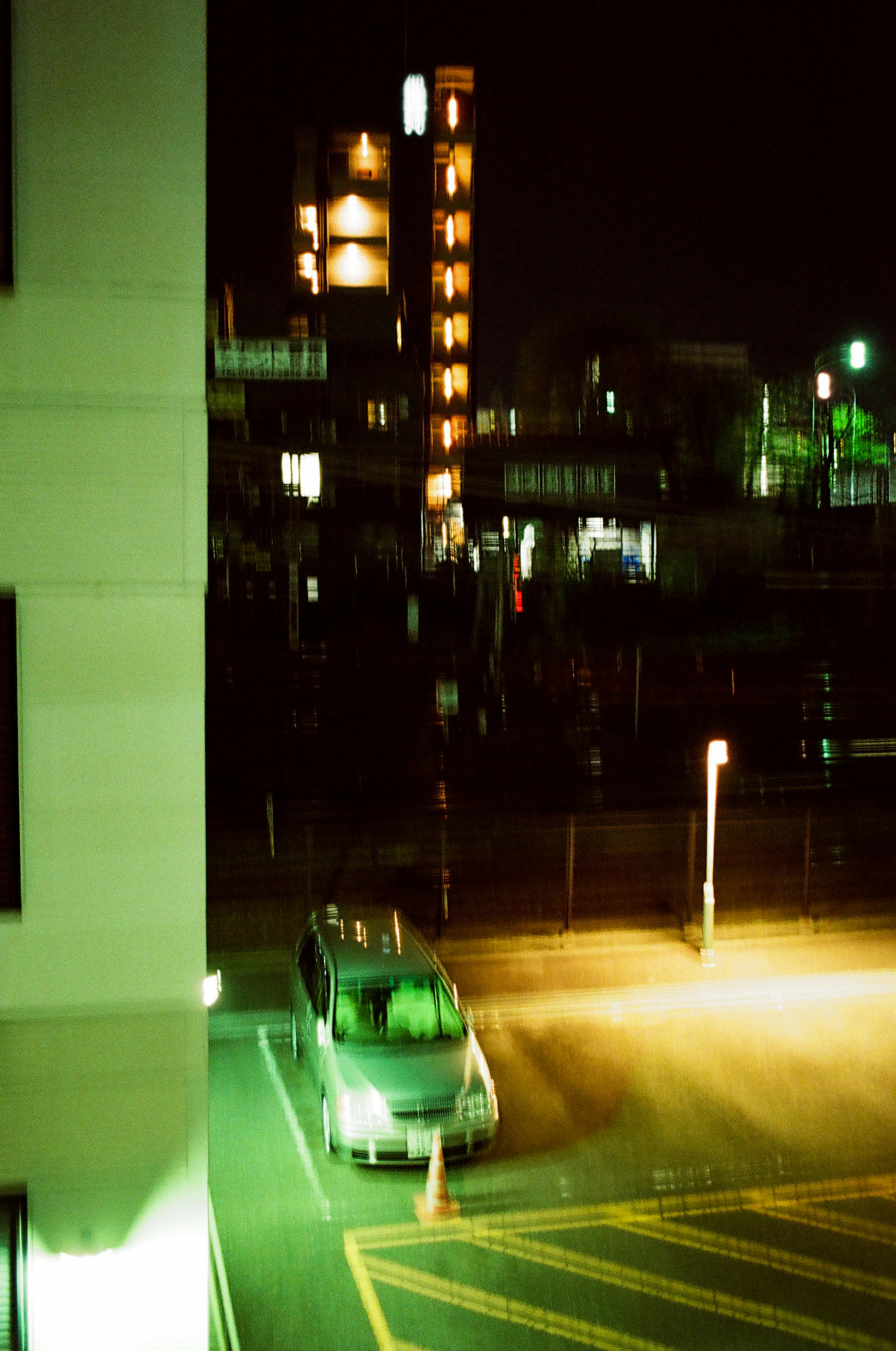 Coche estacionado en un aparcamiento nocturno con luces de edificios circundantes