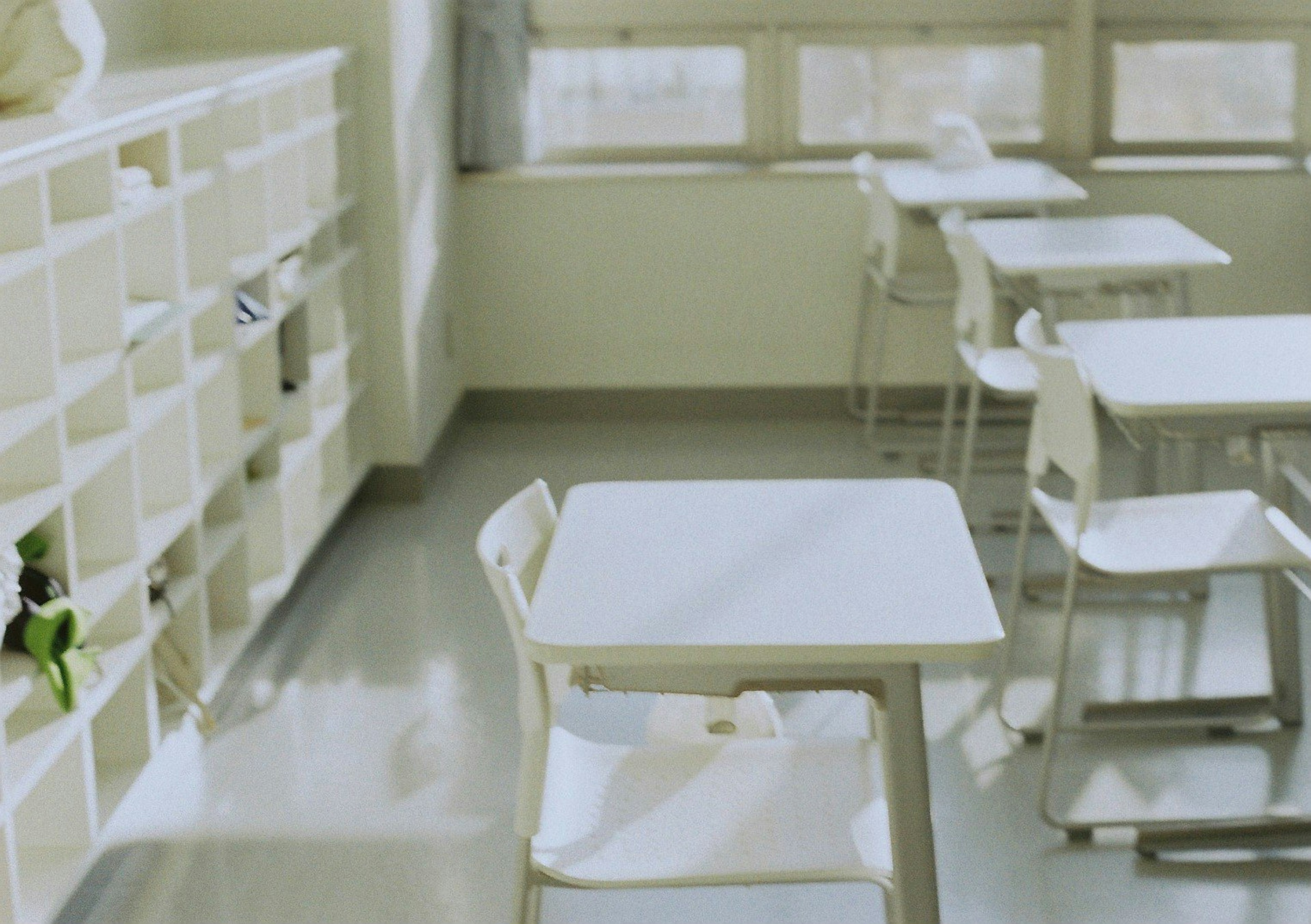 Bright classroom with white desks and chairs alongside a shelf