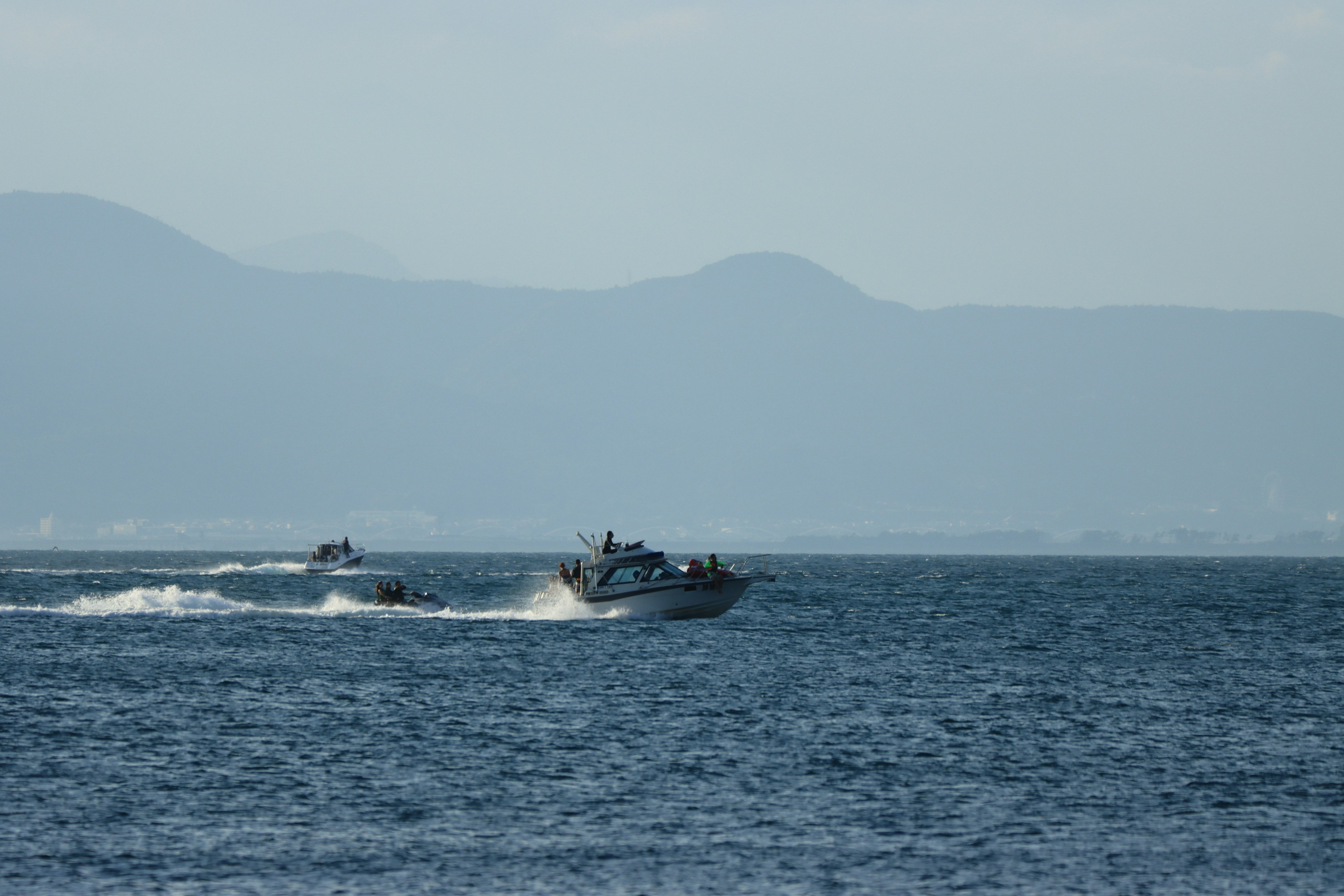 Boats navigating on the ocean with mountains in the background