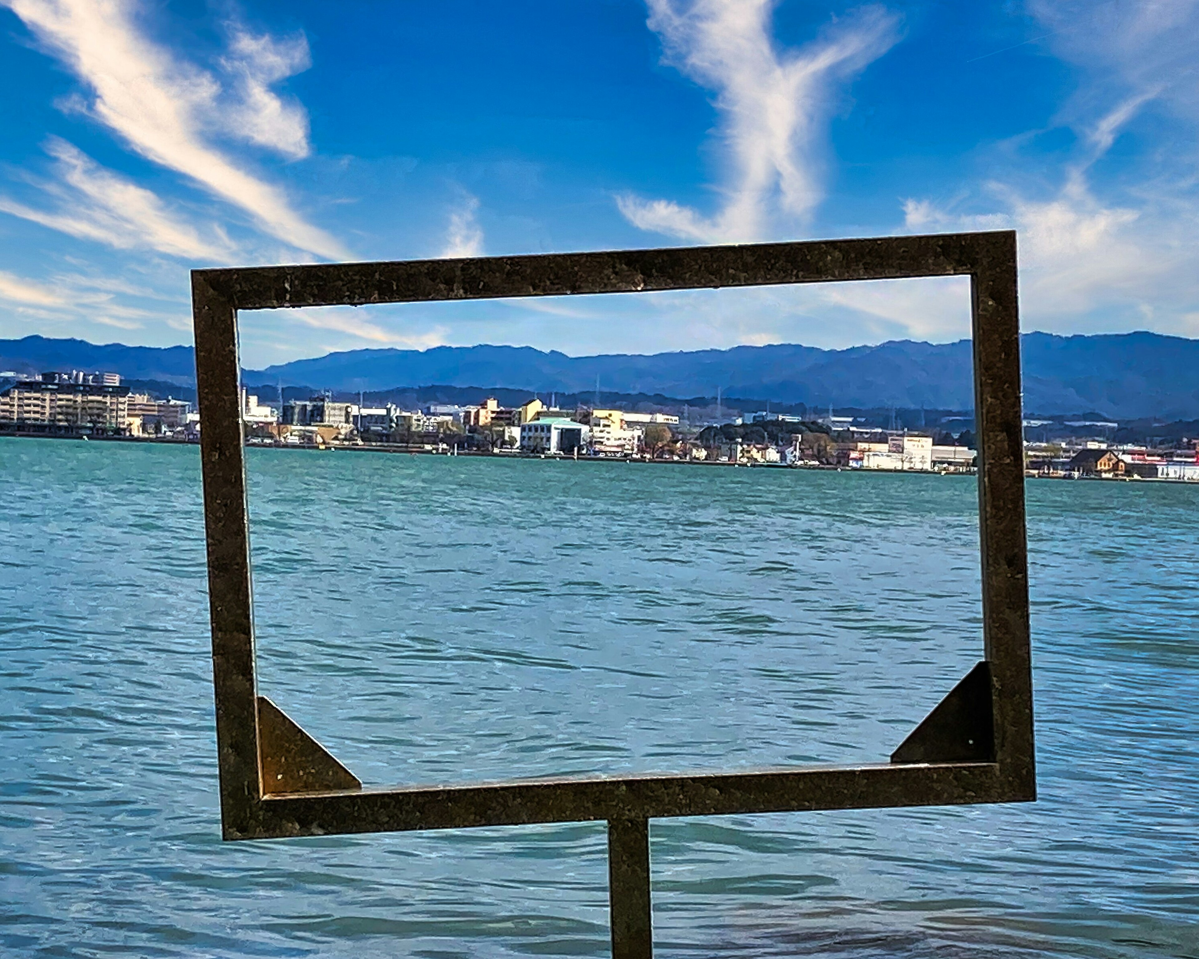 水辺に立つフレームの中に広がる景色と青空