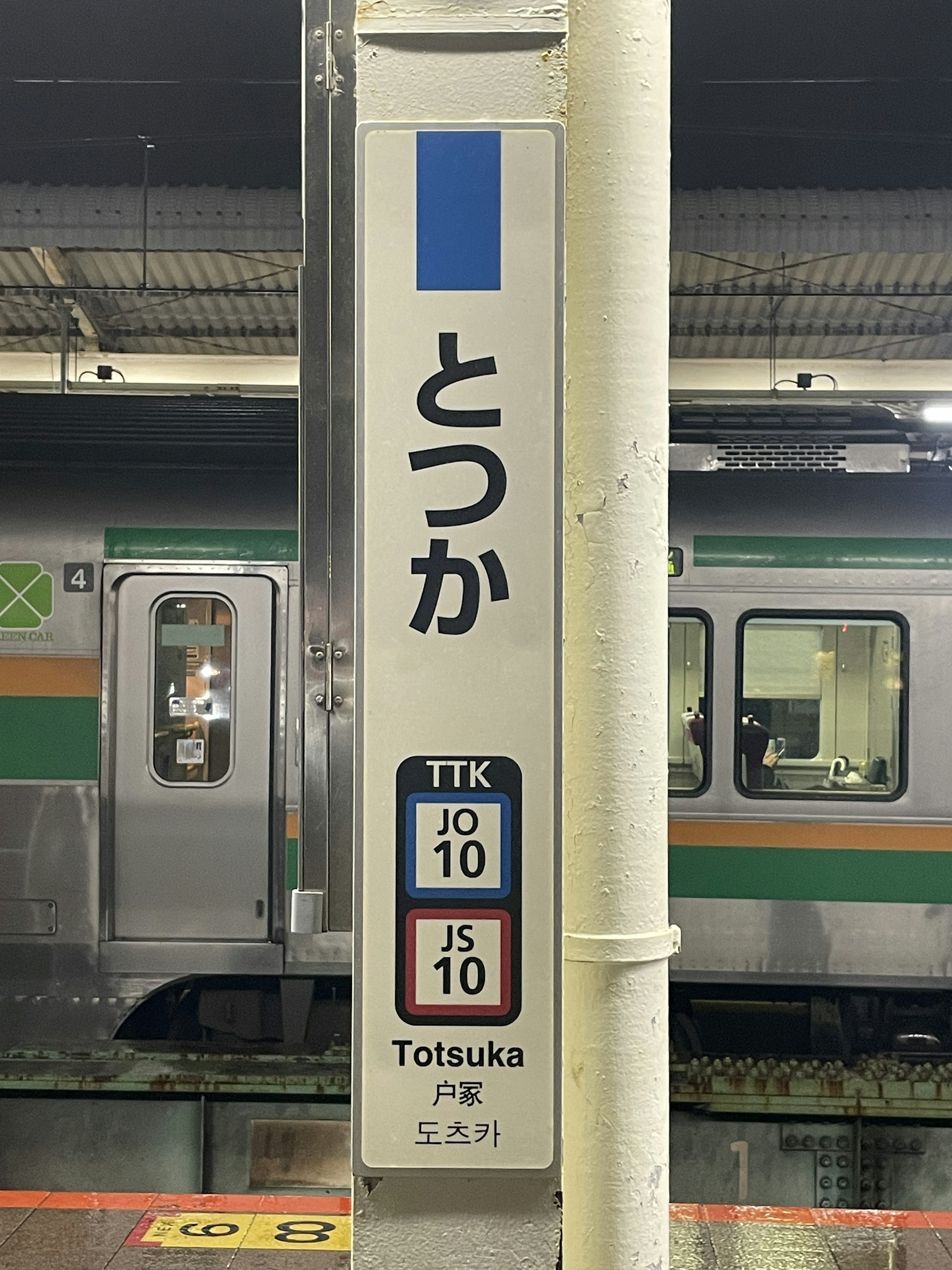 Sign for Totsuka Station with part of a train visible