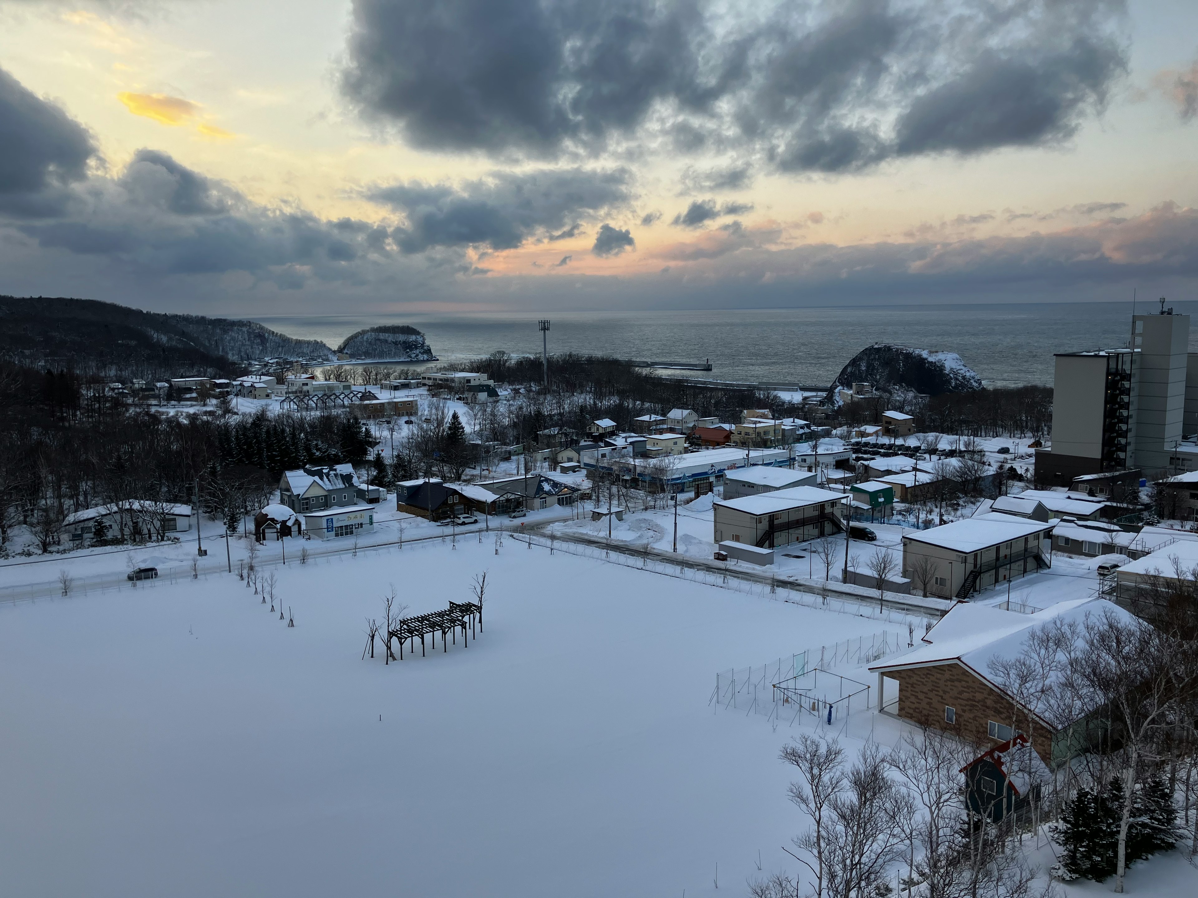 雪に覆われた町と海の景色夕焼けと雲が広がる空