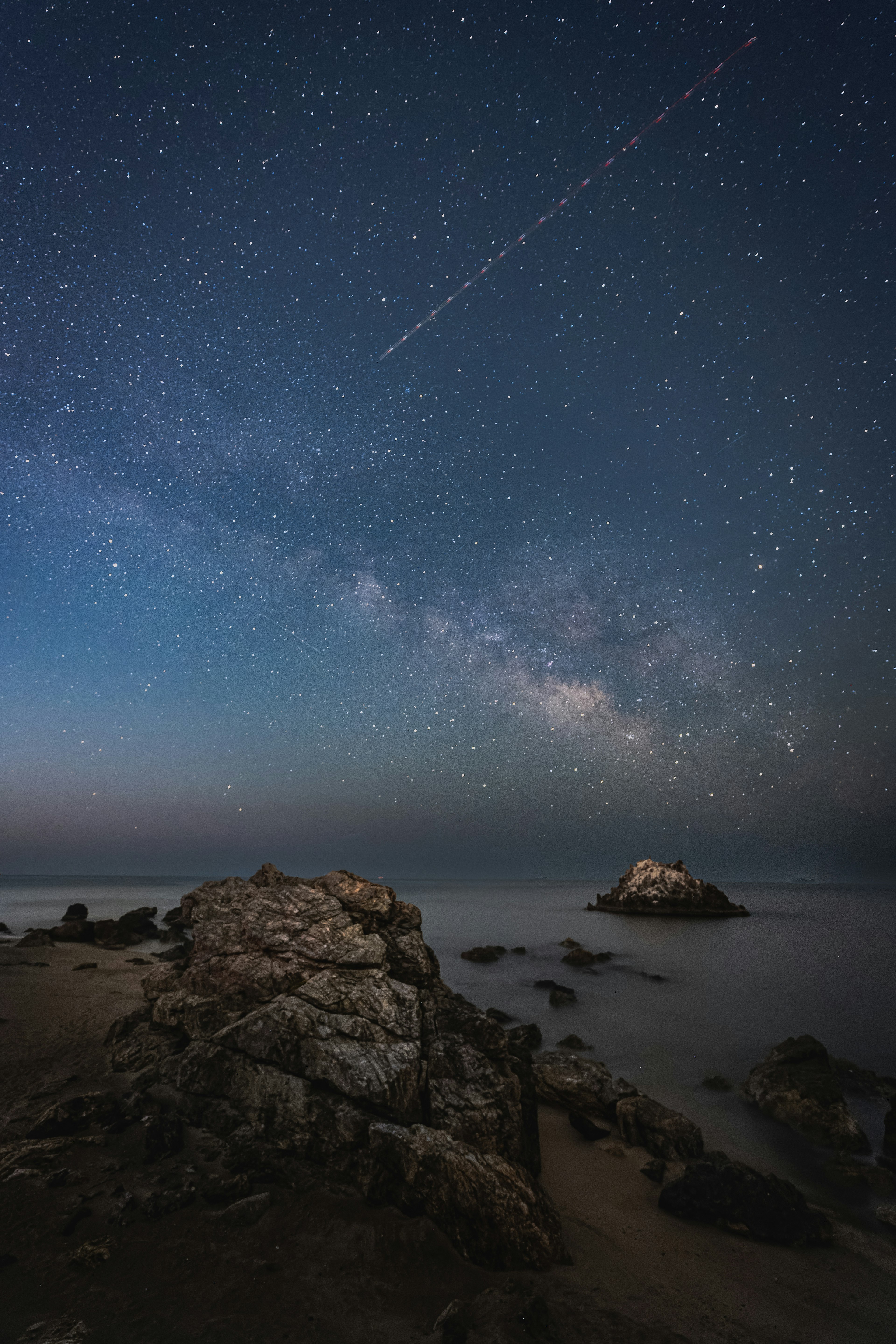 Une scène côtière sereine sous un ciel étoilé avec des formations rocheuses