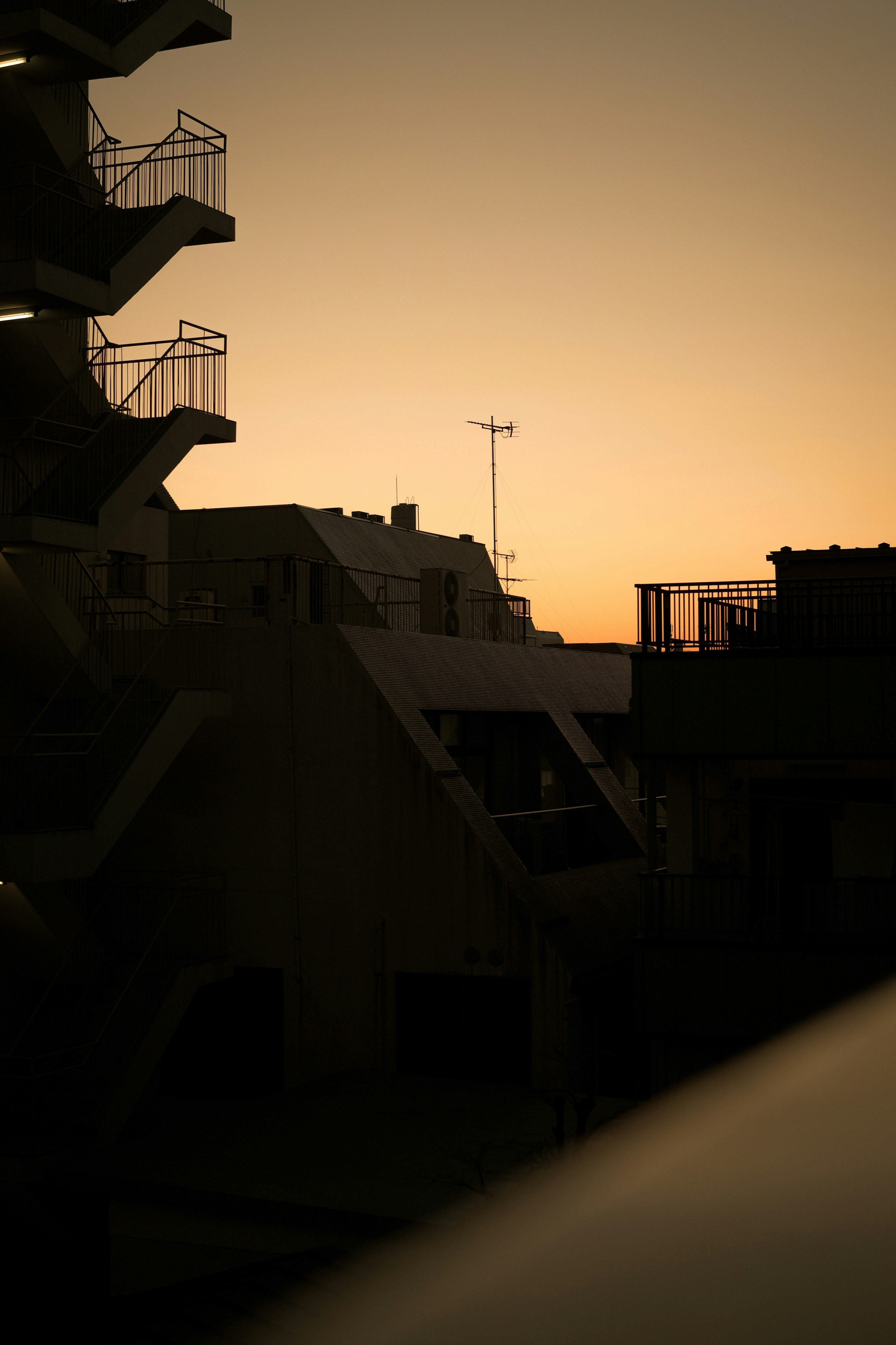 Silhouetted buildings and staircases against a sunset sky