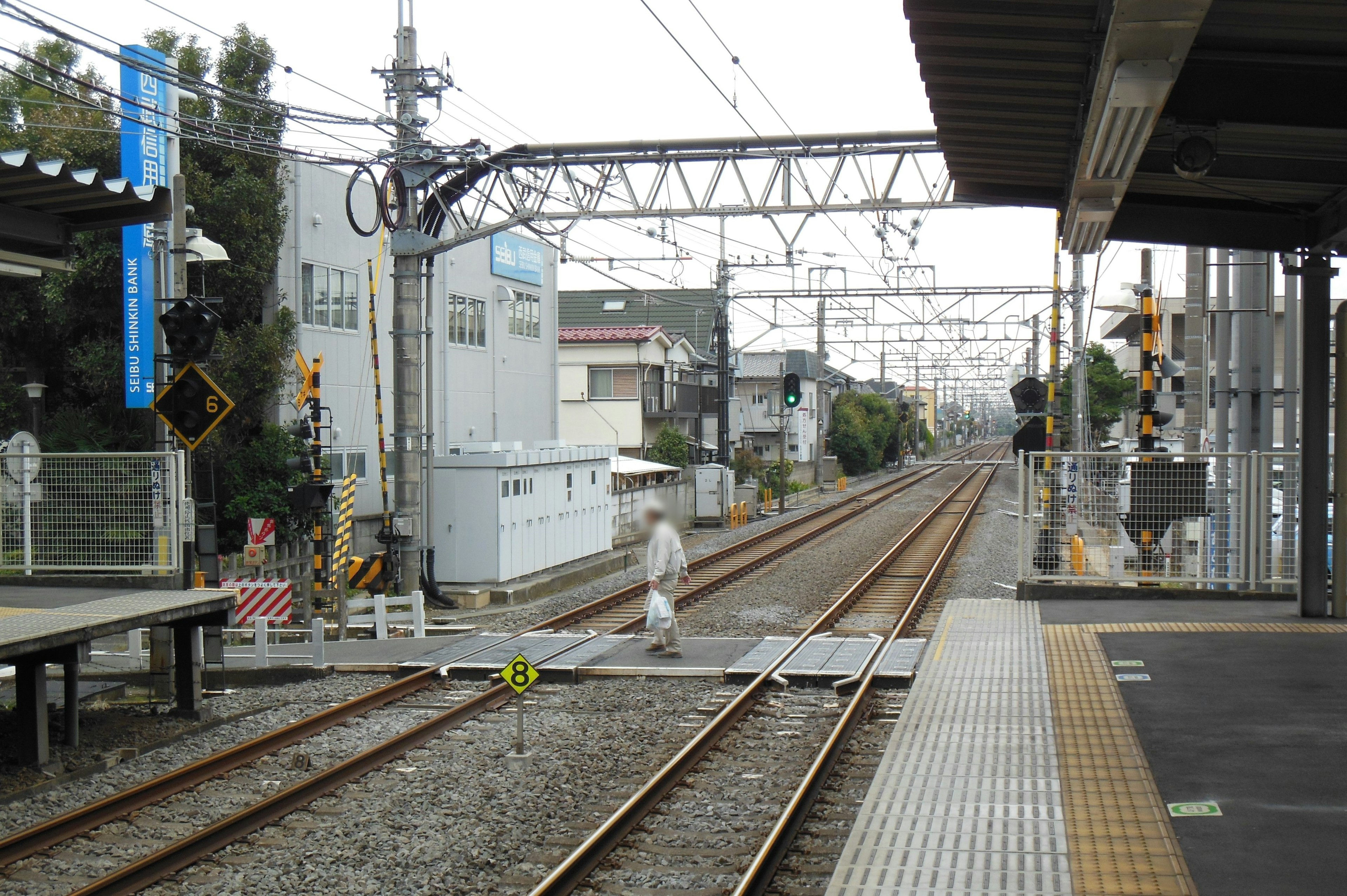 Train station platform with tracks and a person crossing the railway