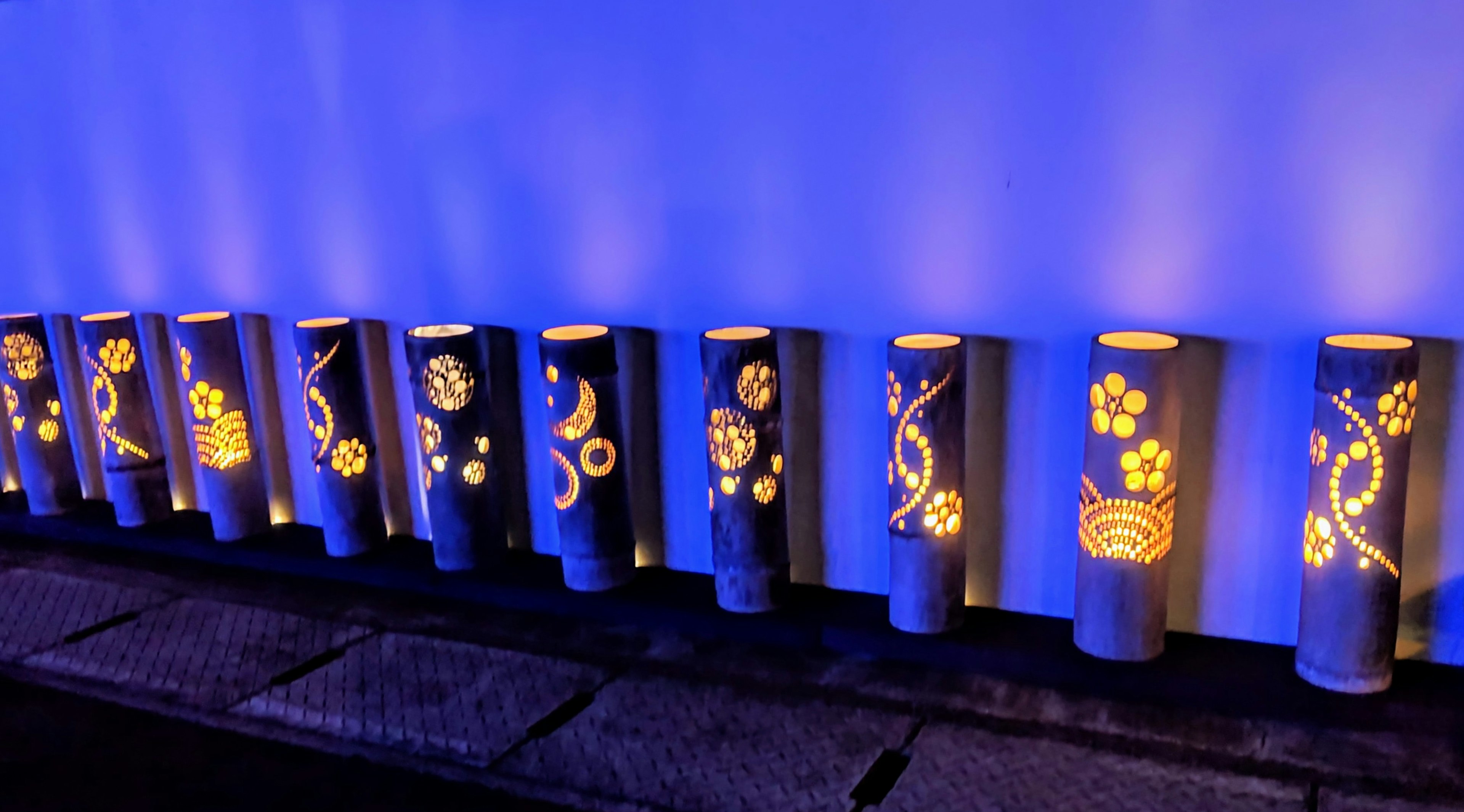 A row of beautifully designed bamboo lamps illuminated against a blue background