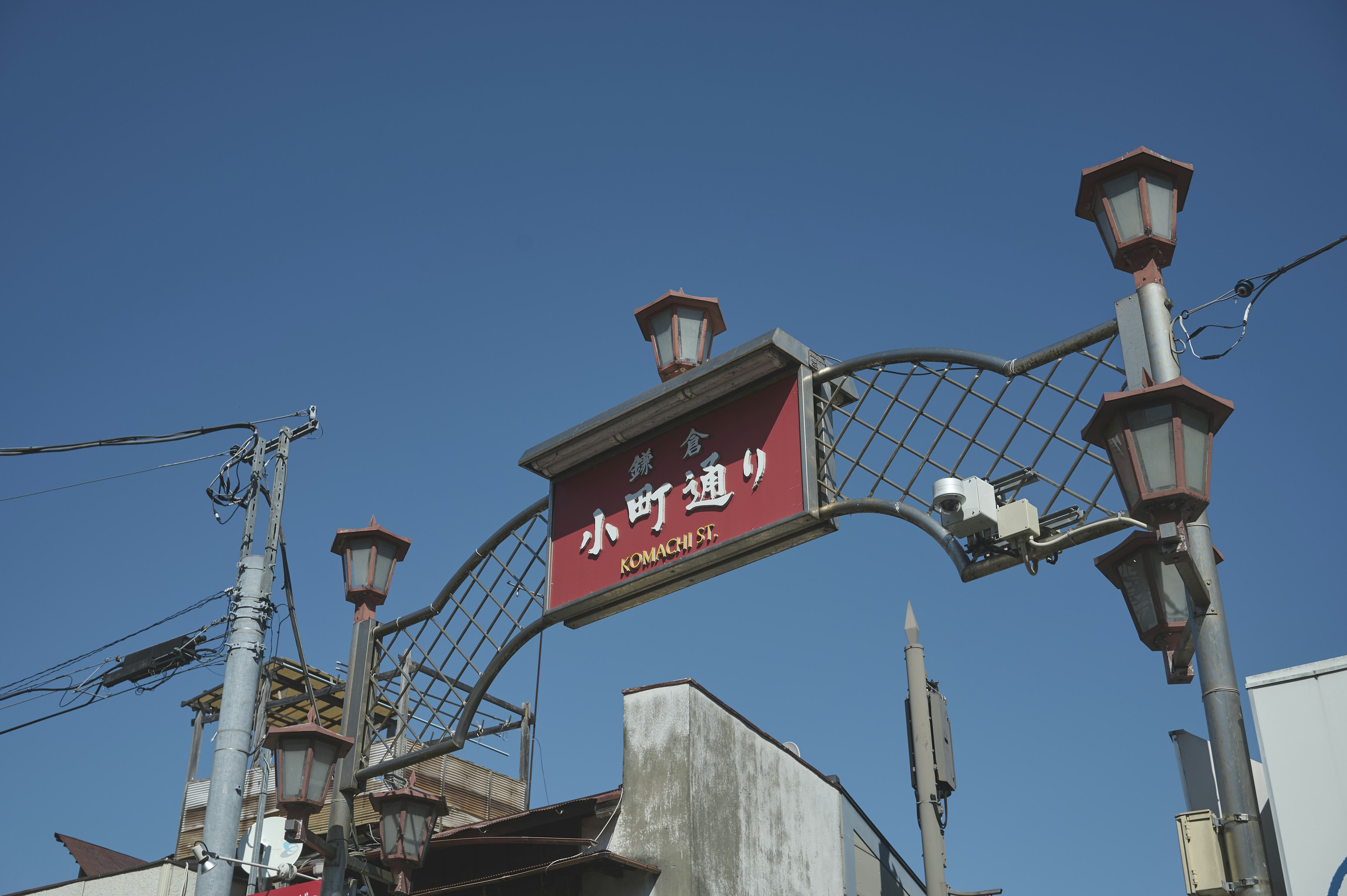 Sign for Komachi Street under a clear blue sky with street lamps