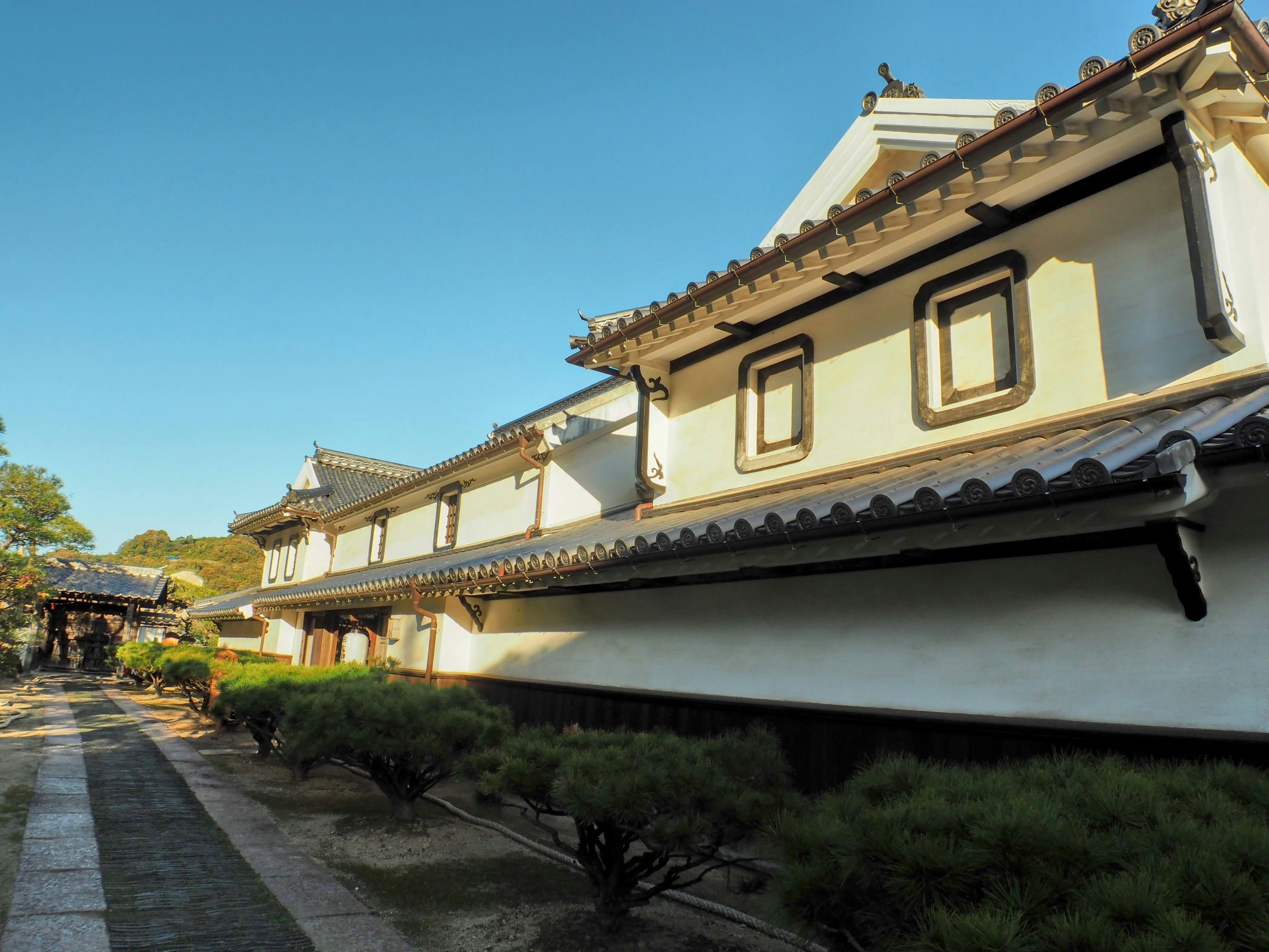 Casa japonesa tradicional con paredes blancas y un jardín verde con un camino de piedra