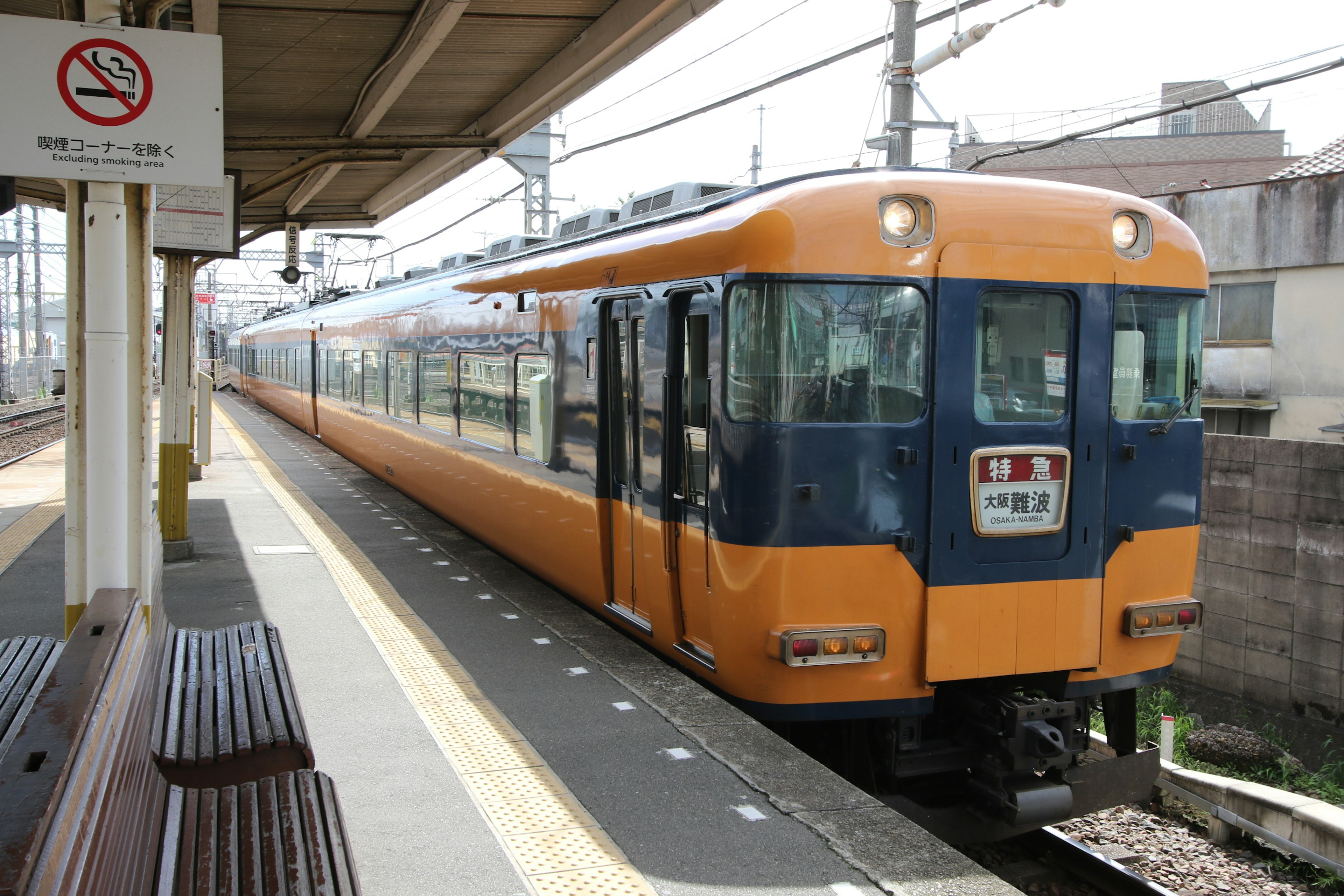 An orange and blue train parked at a station