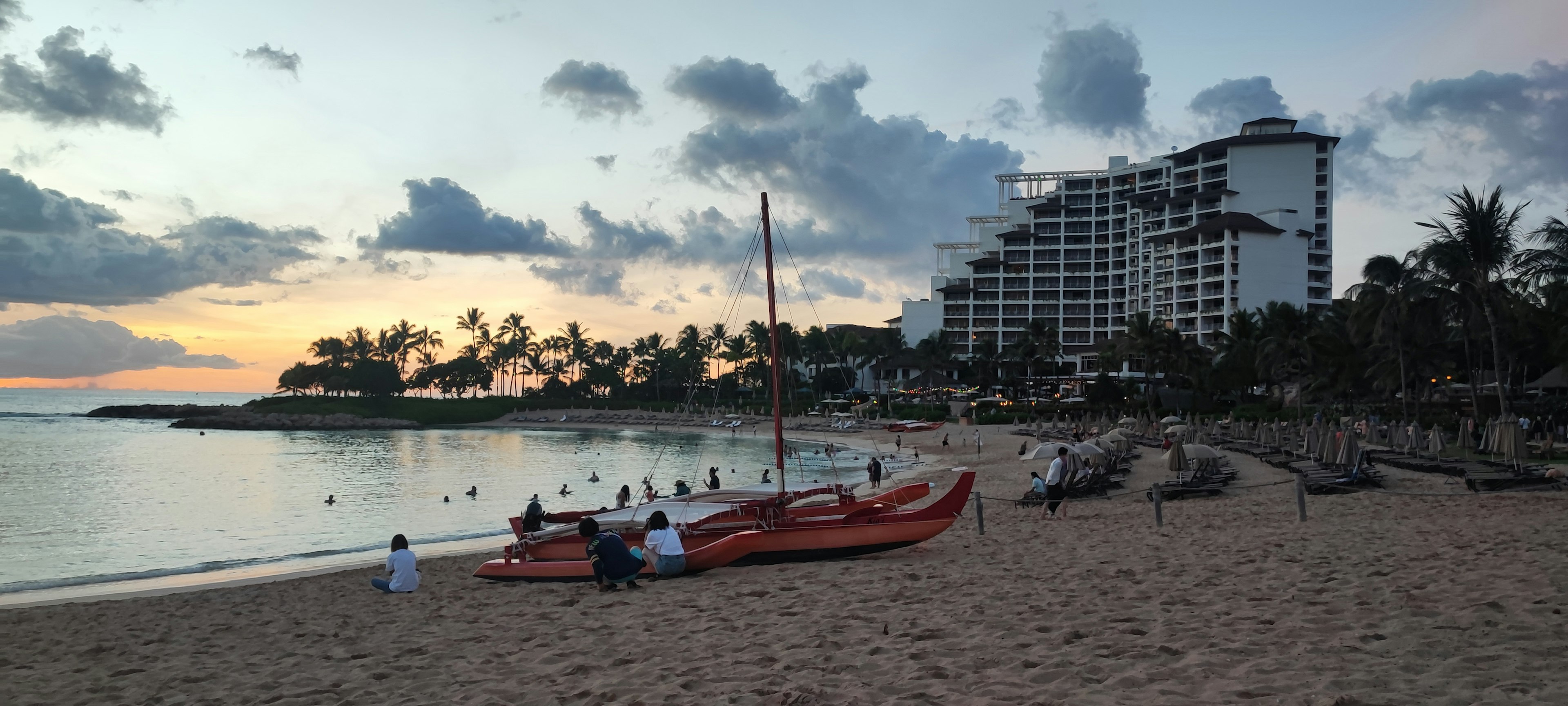 日落時的海灘景觀，紅色獨木舟和度假酒店