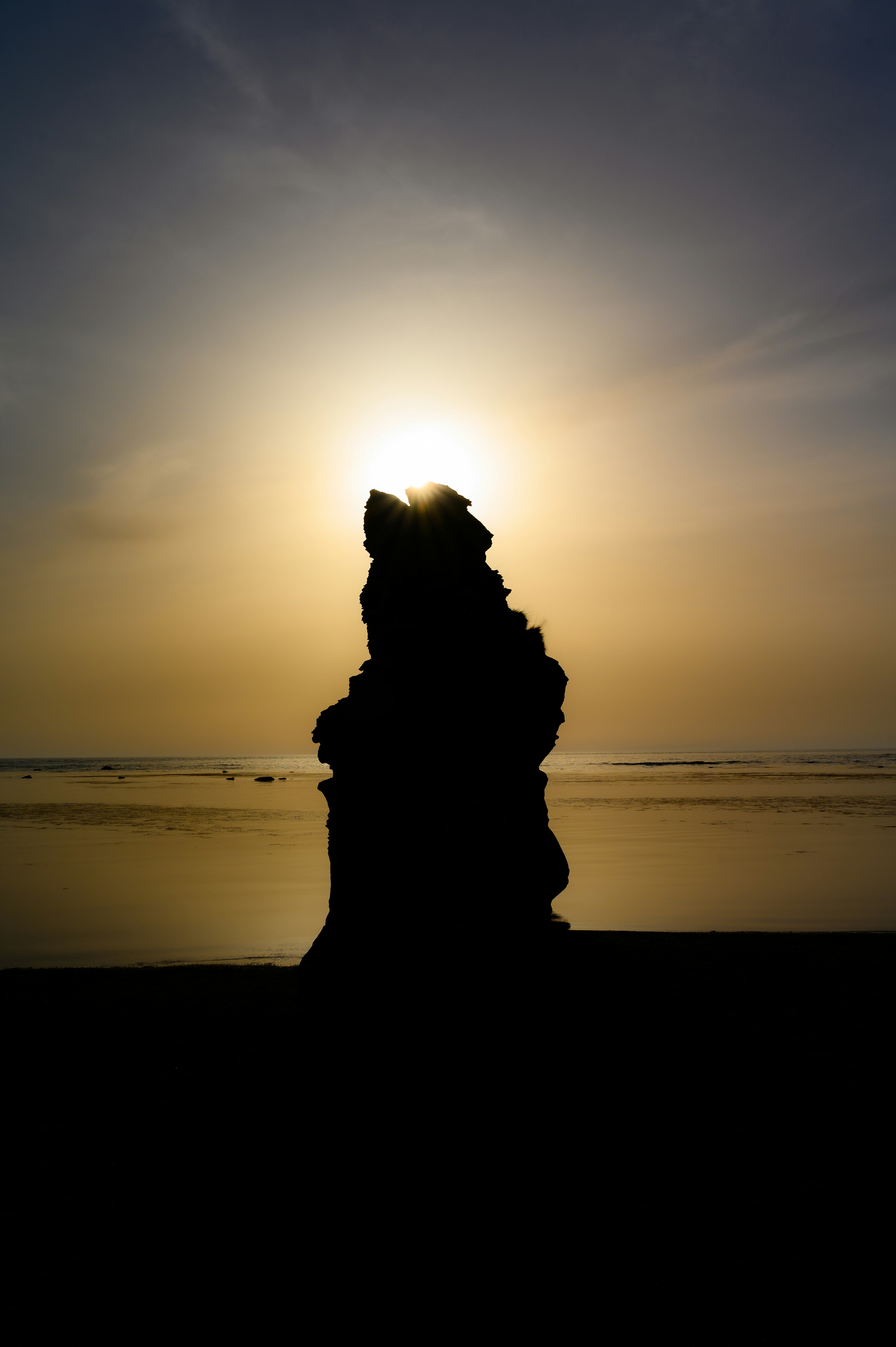 夕日を背景にした海岸の岩のシルエット