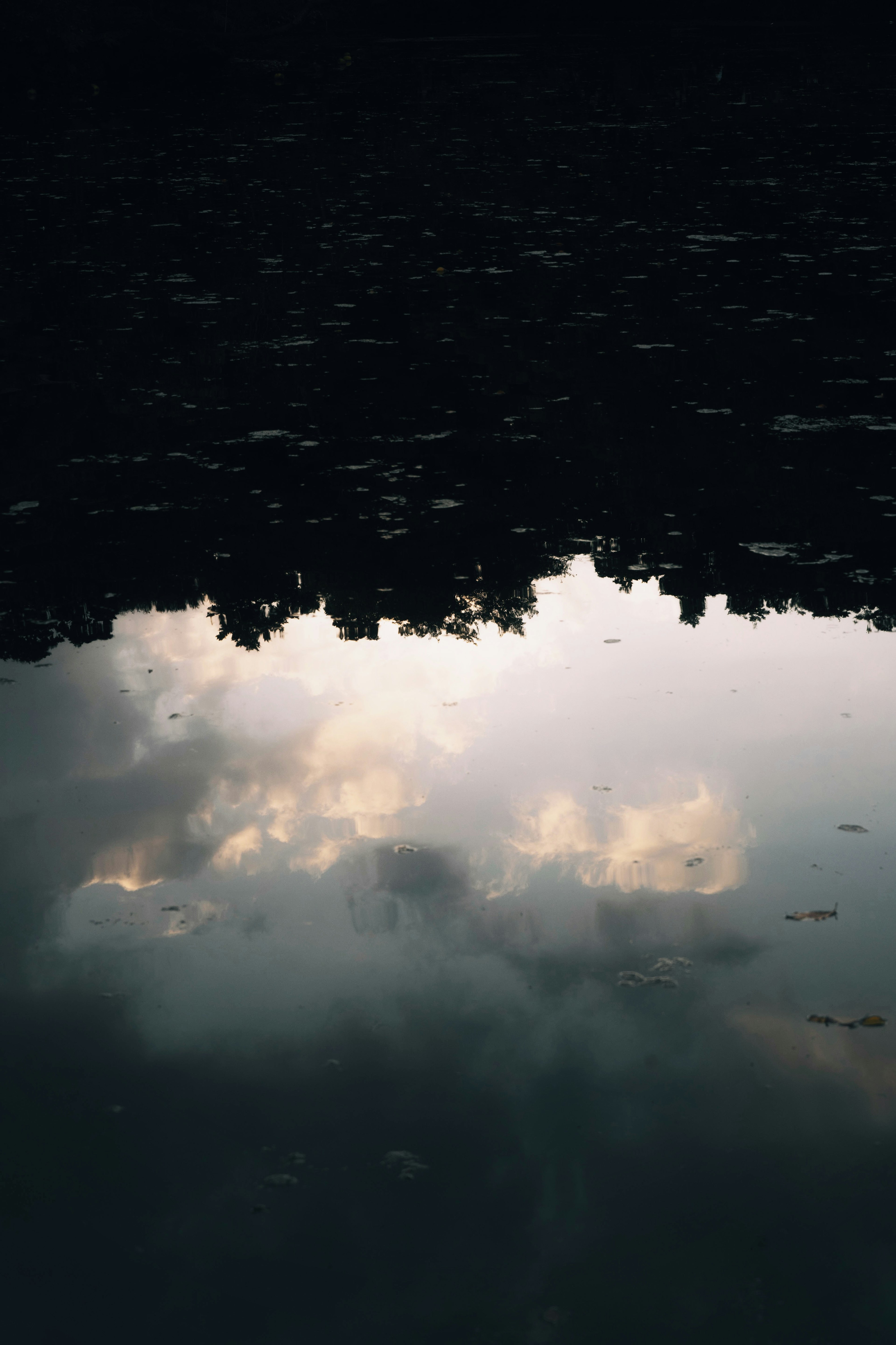 Reflexion von Wolken auf einer dunklen Wasseroberfläche