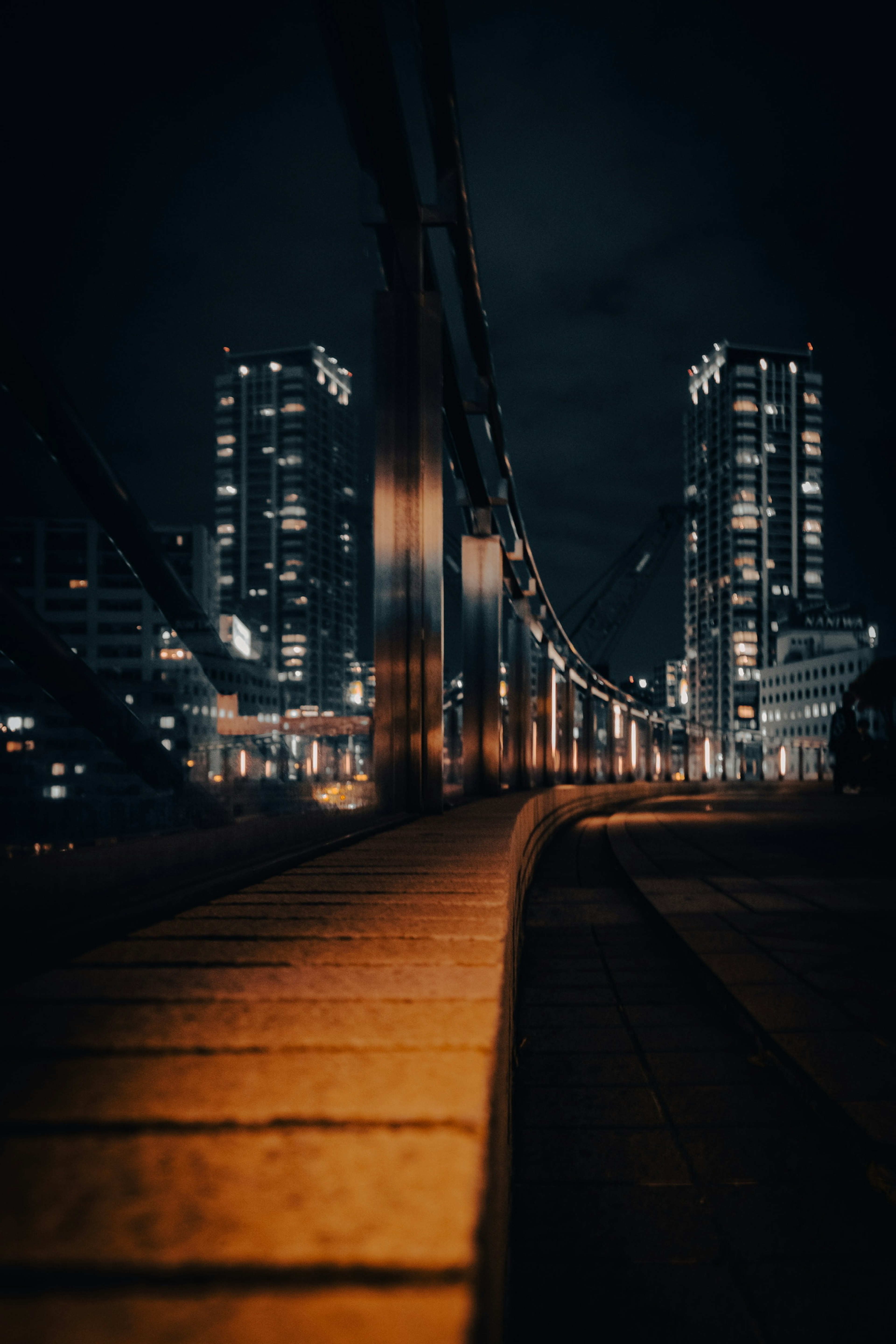 Low-angle view of a bridge at night with illuminated skyscrapers in the background