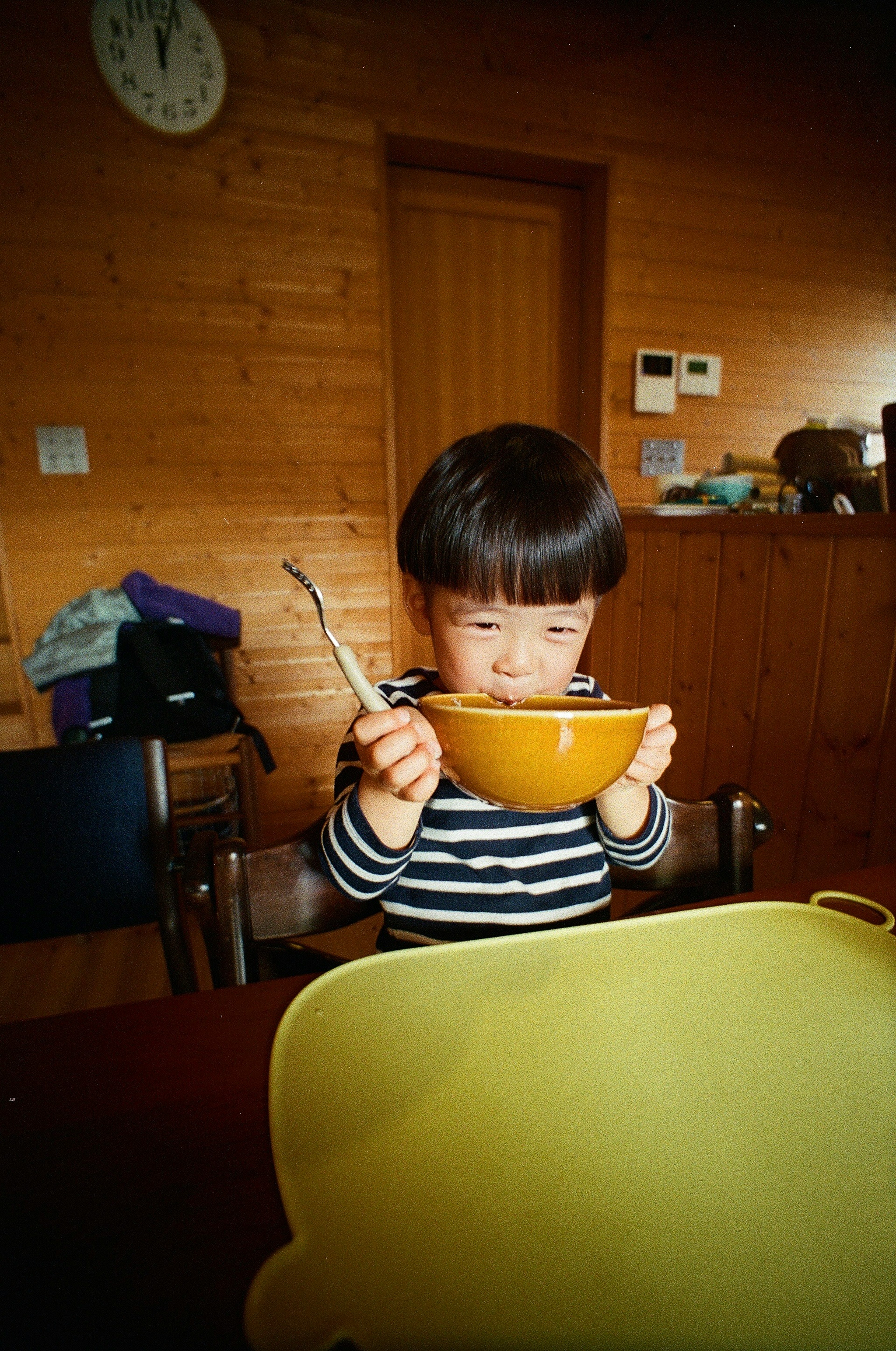 Child in striped shirt holding orange bowl