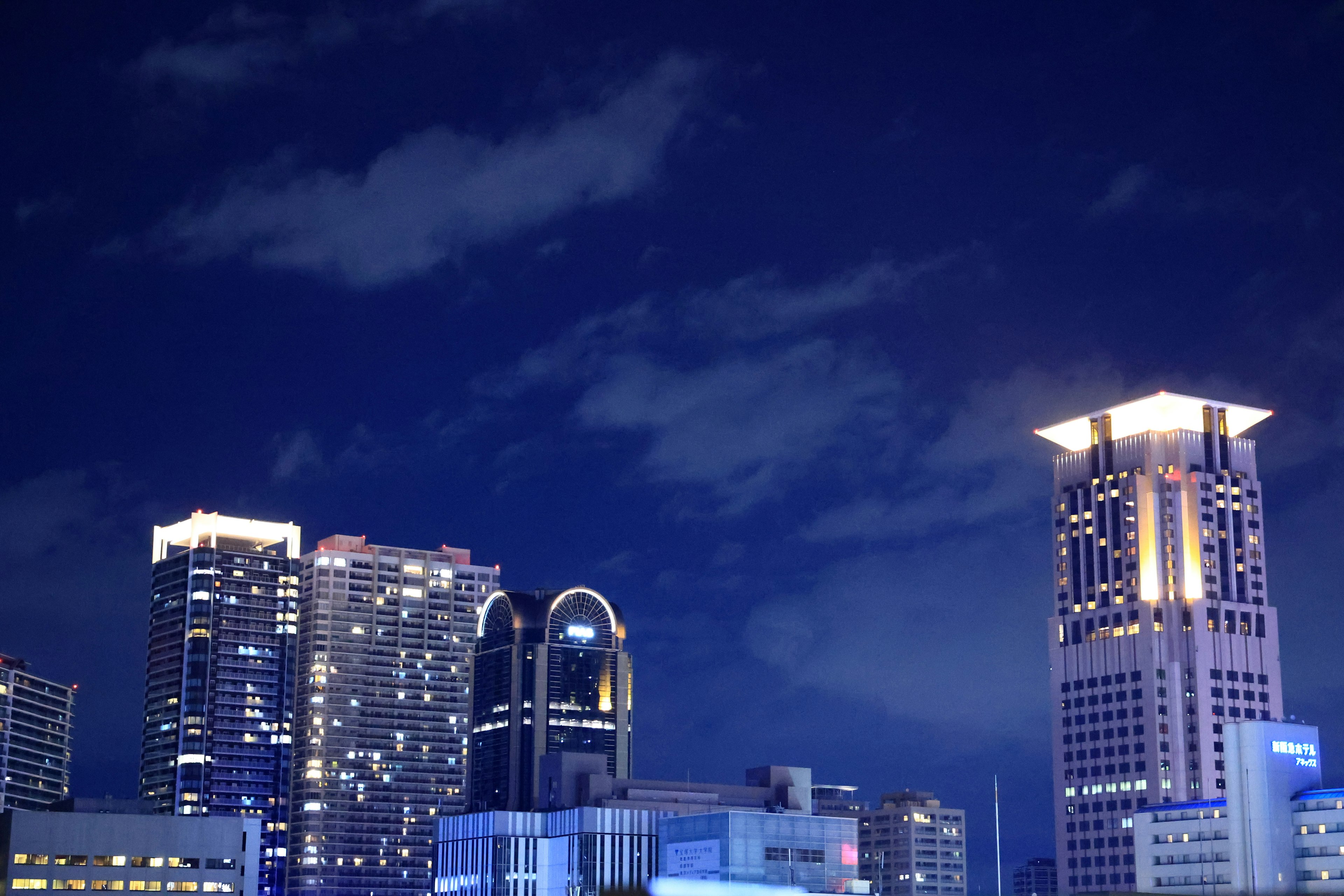 Night cityscape with illuminated skyscrapers and a cloudy sky