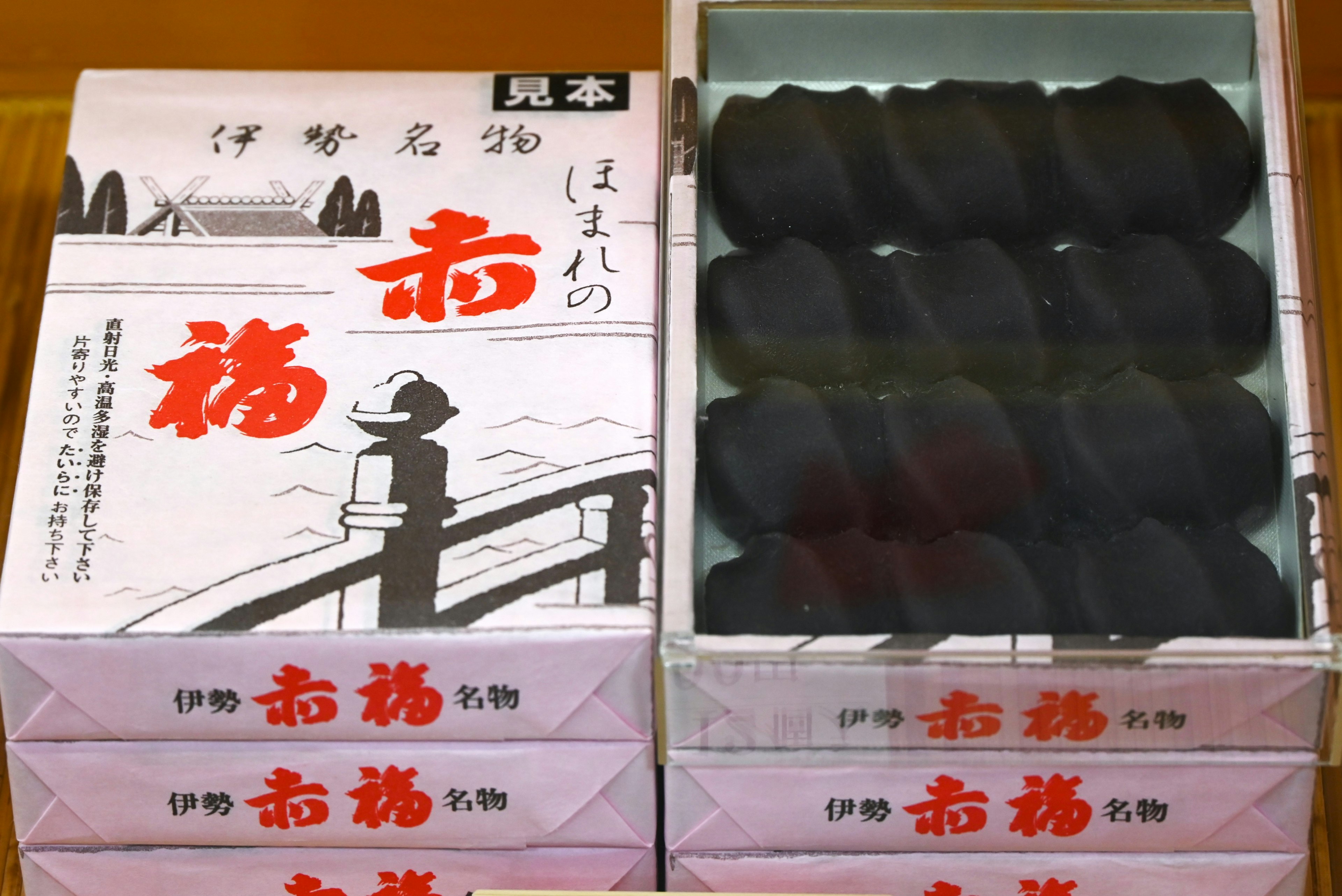 Image of a box containing black Japanese sweets with traditional packaging design