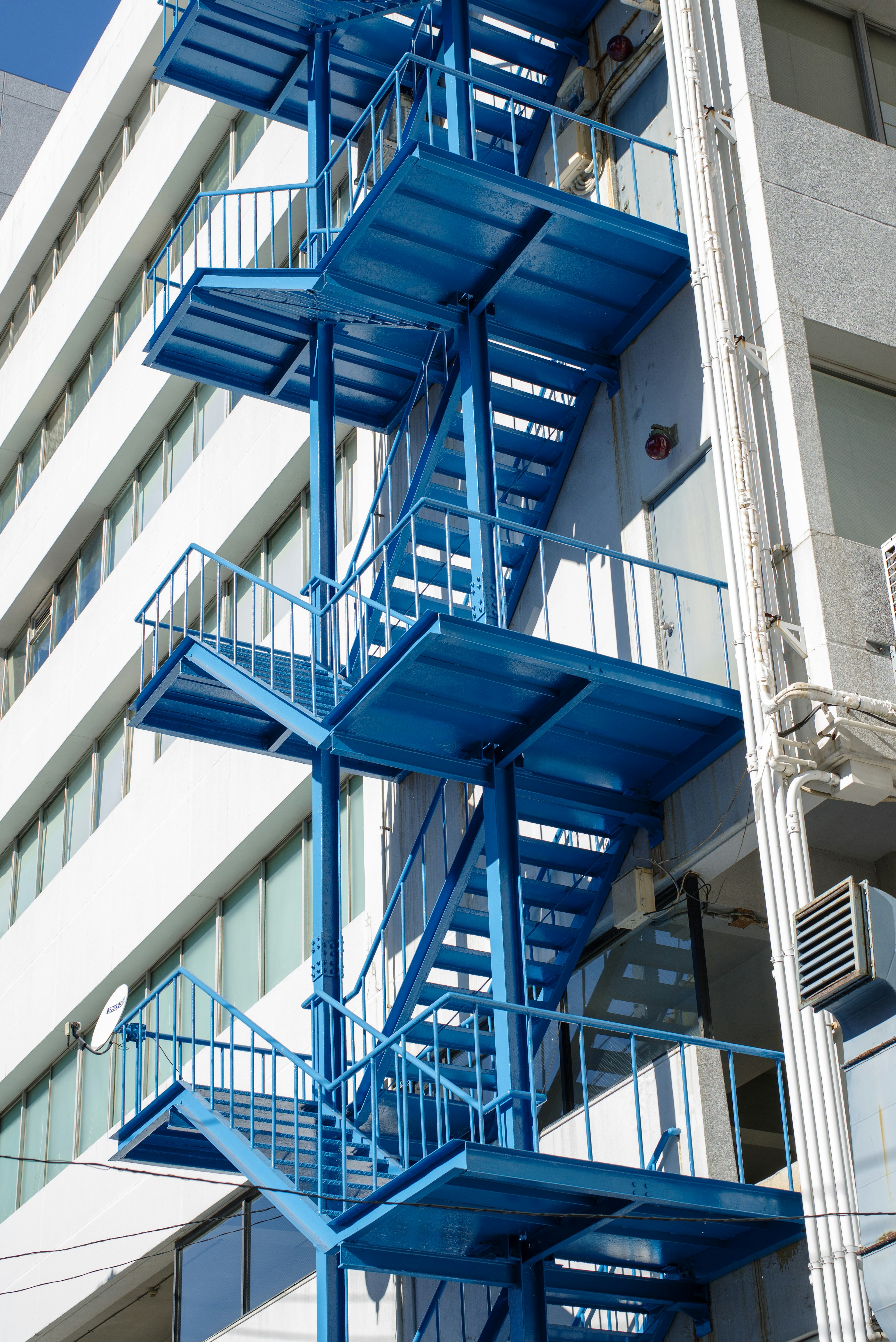 Exterior de un edificio con una escalera de incendios azul