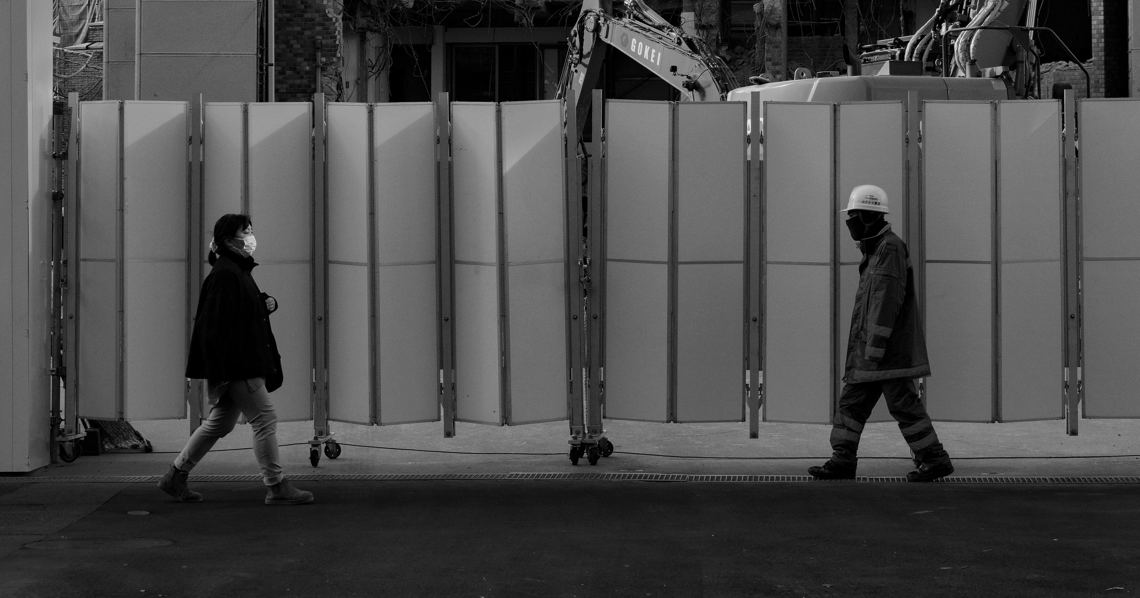 Deux personnes marchant devant une barrière de chantier