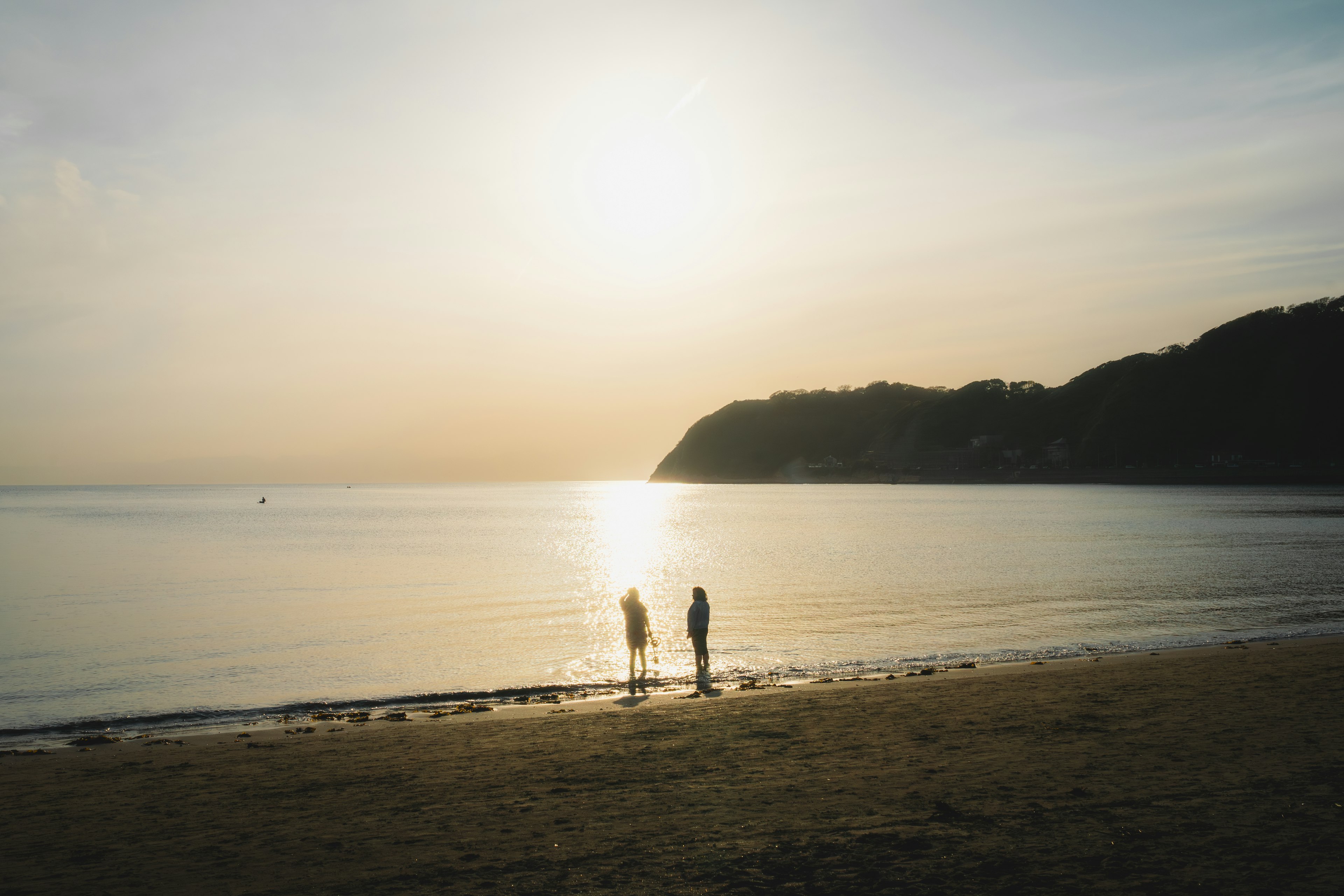 夕日を背景にした海岸で立っている二人のシルエット